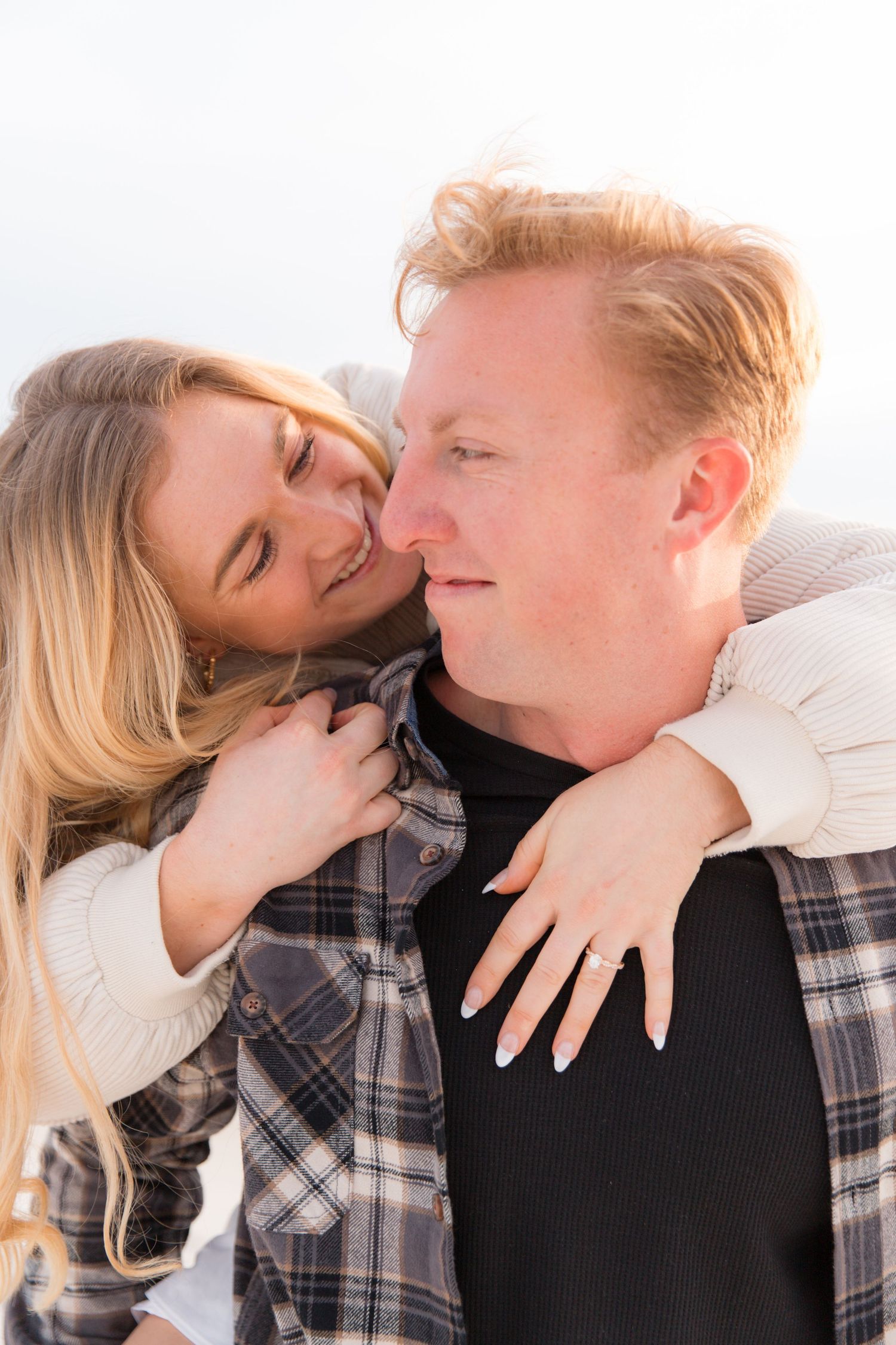 Close-up romantic moments captured between couple wearing plaid and white sweater.