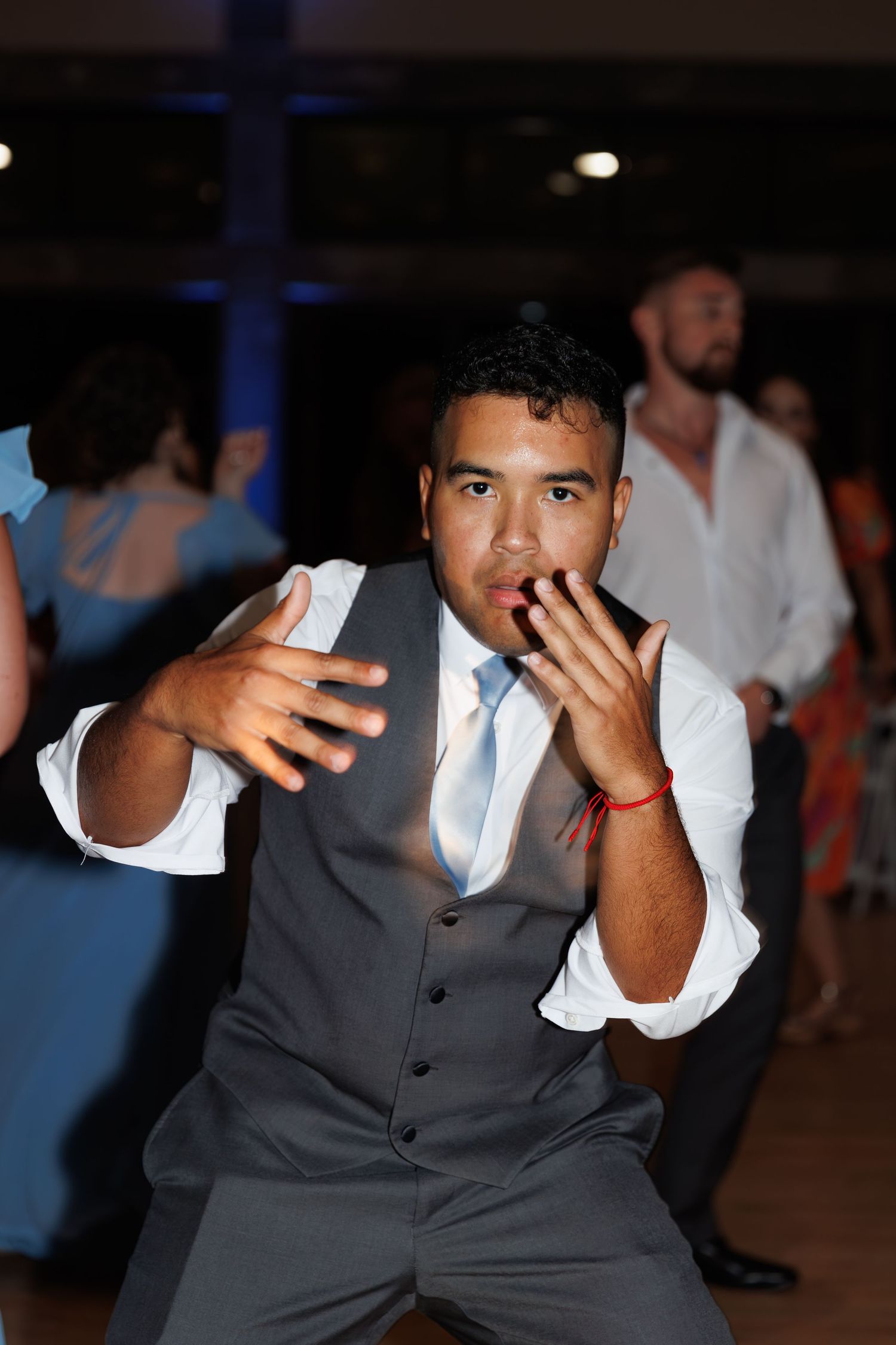 Wedding guest in formal attire dancing energetically at reception.