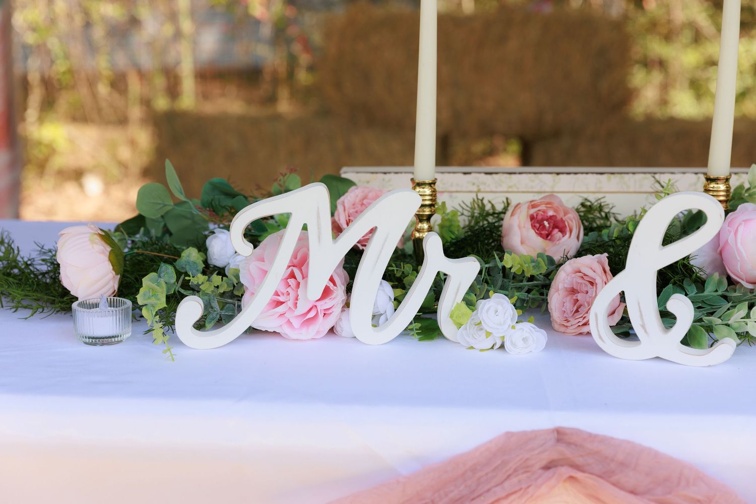 Pink roses and white decorative elements create an elegant wedding reception table setting.