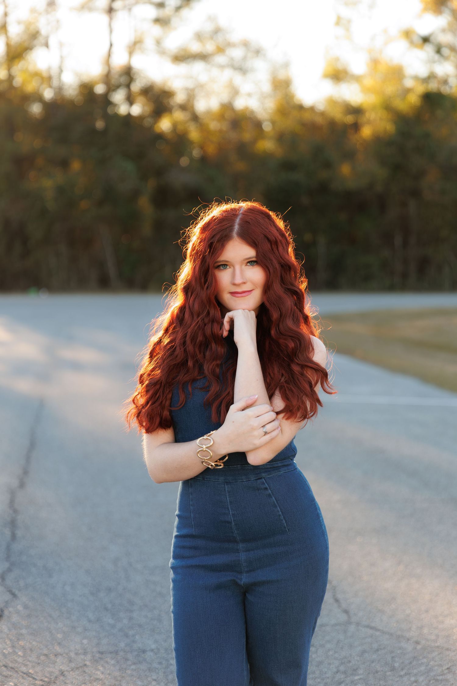 A person wearing high-waisted jeans poses outdoors during golden hour on a gravel path.