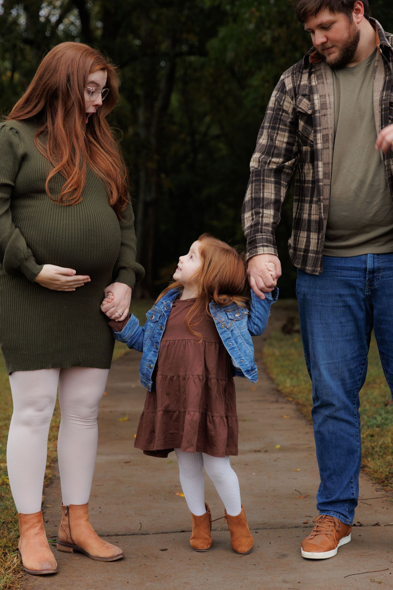 Family wearing coordinated fall outfits with plaid shirts and brown boots standing together on a stone path.