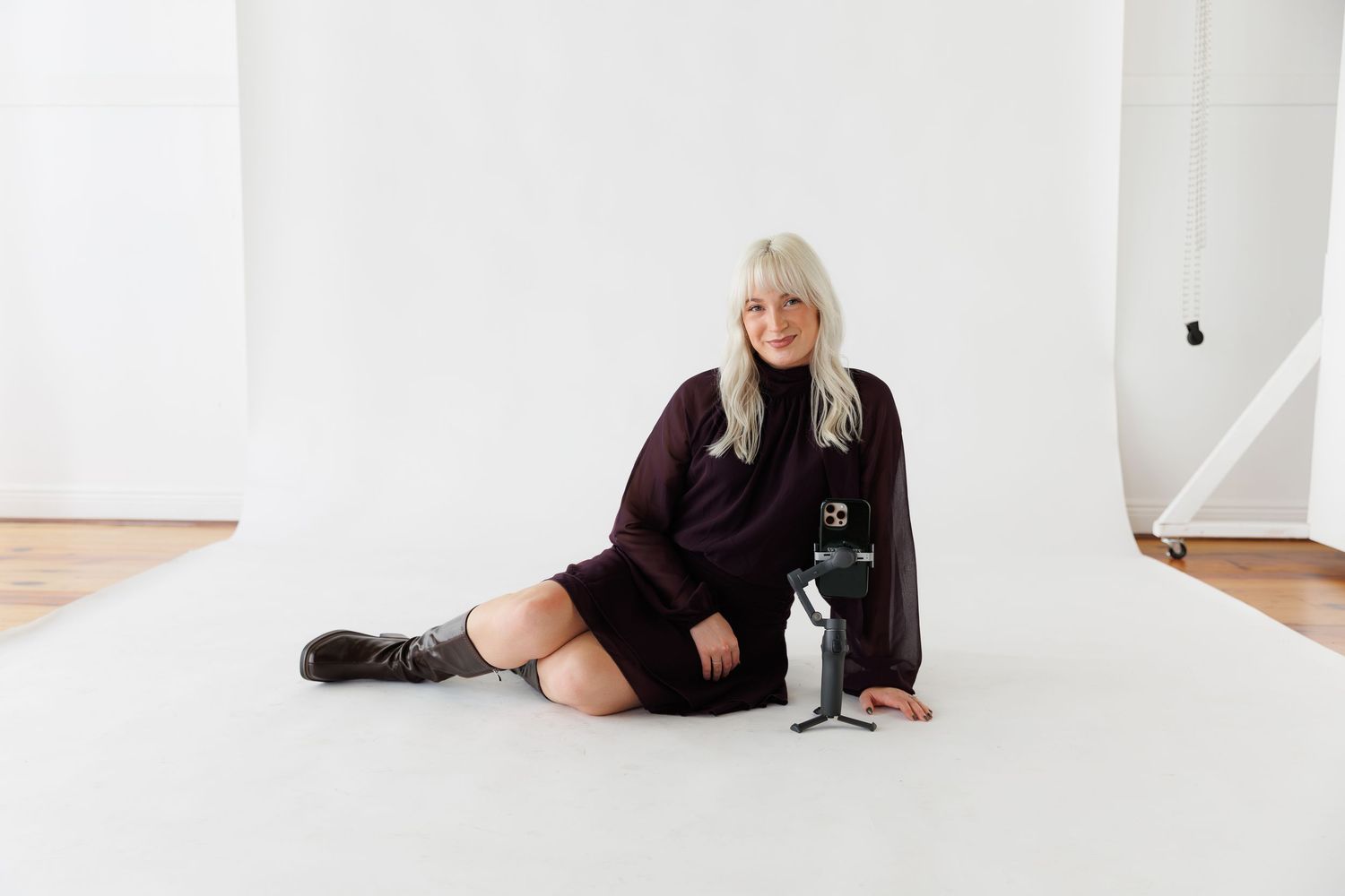 A person in black clothing lies on a white floor in a bright minimalist space.