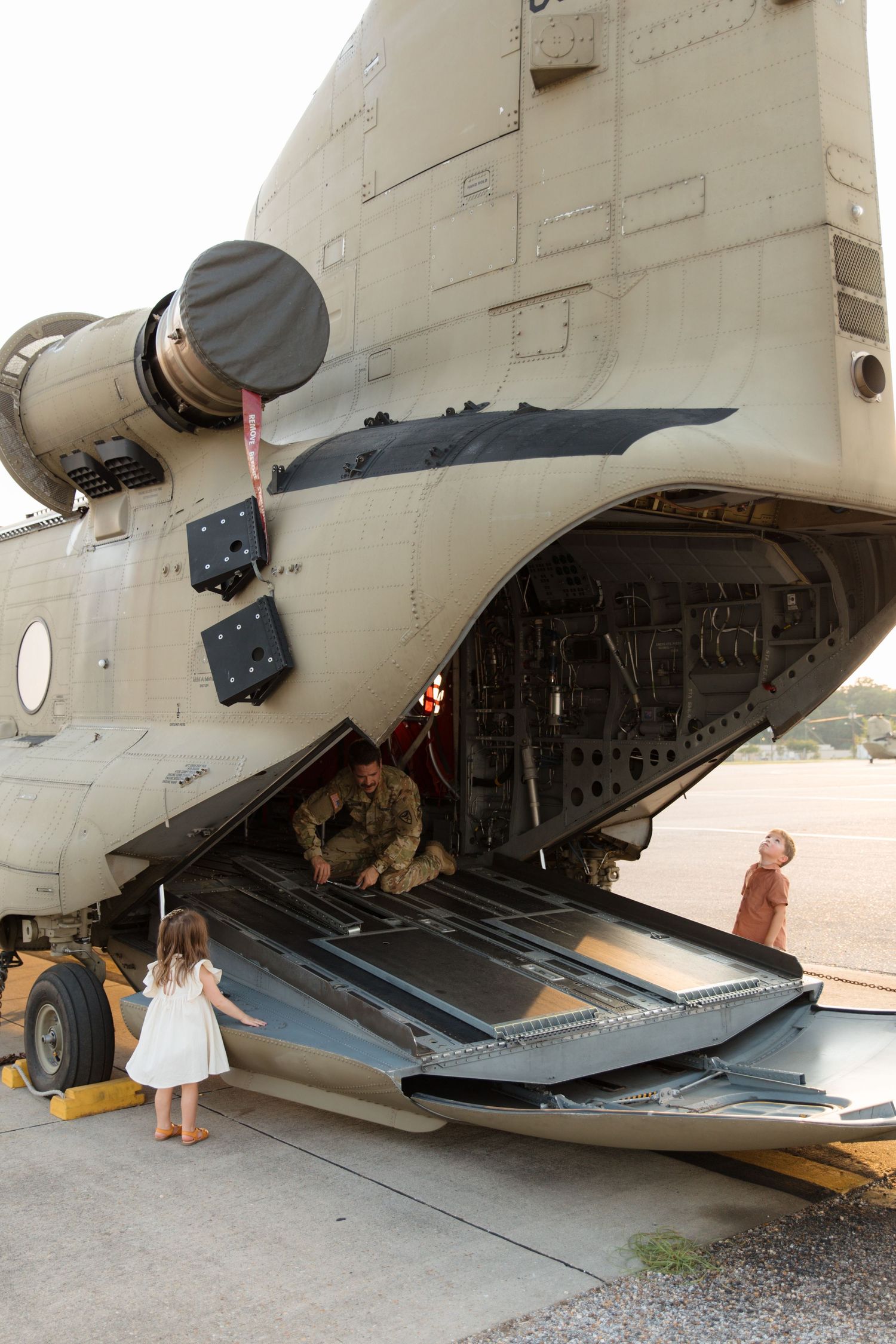 Young children explore military helicopter ramp while wearing casual attire.
