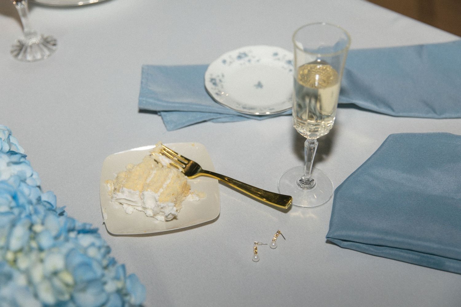 Wedding reception table setting with blue napkins and champagne glass.