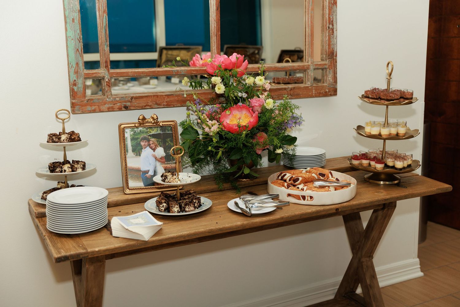 A rustic wooden table with tiered dessert stands and floral centerpieces set for an elegant event.