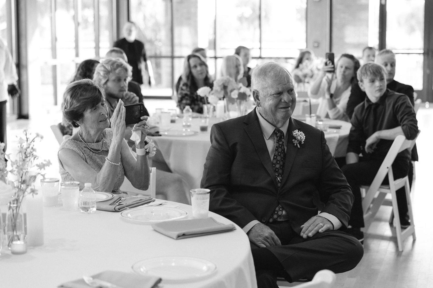 Black and white candid reception photo of wedding guests enjoying the celebration.