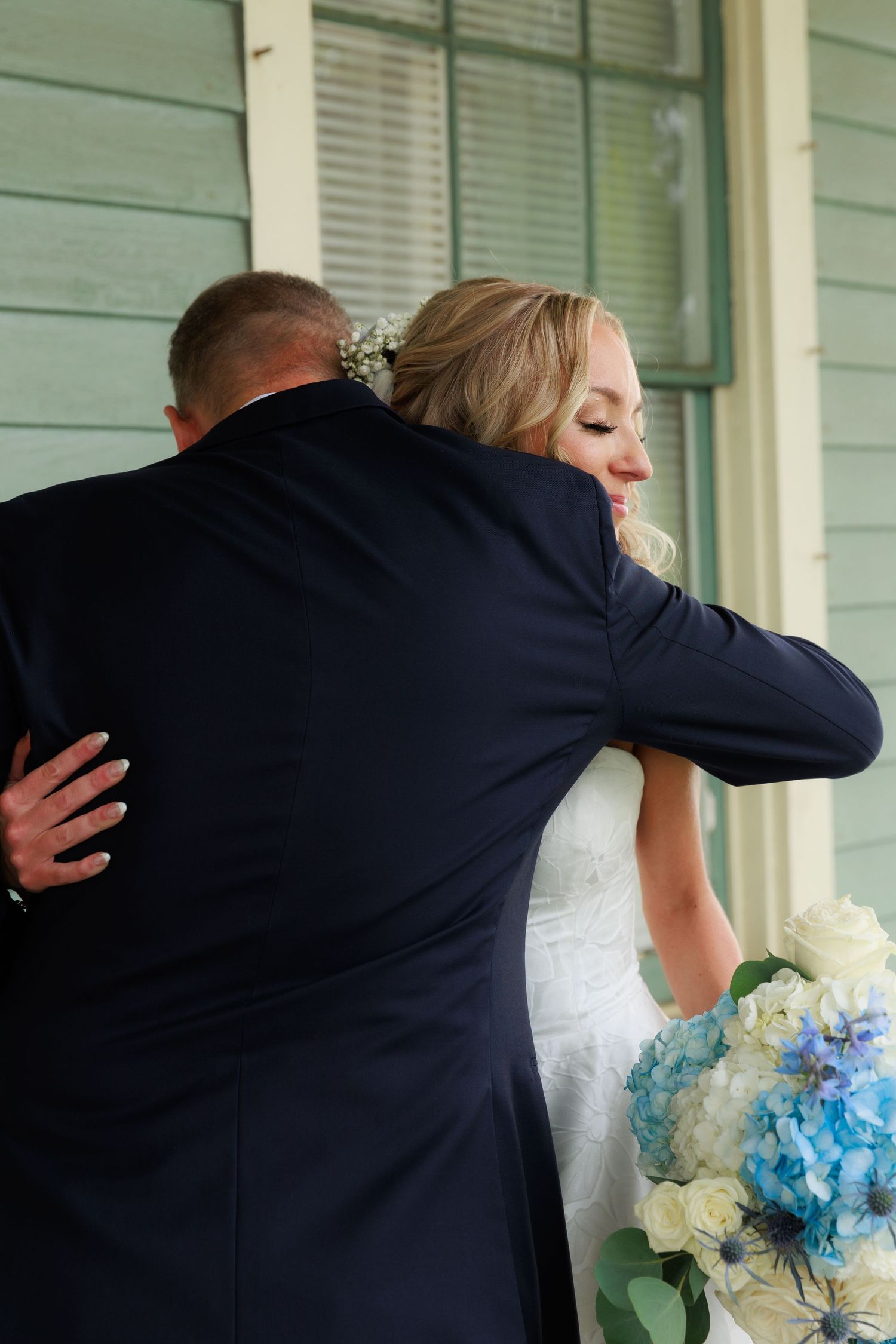Tender embrace shared during wedding first look on vintage porch.