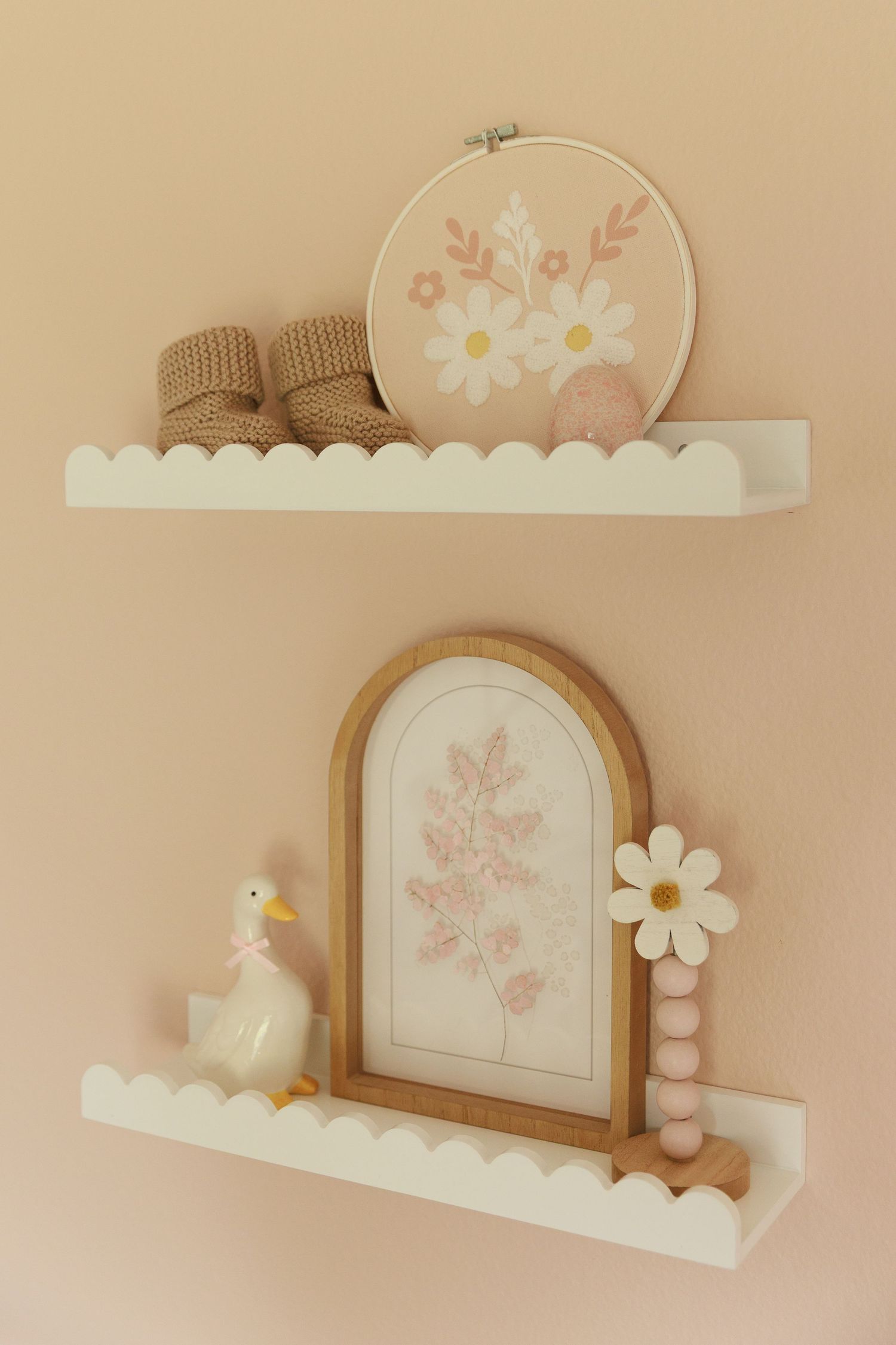 Pastel pink and white decorative wall shelves with floral designs and arched shapes create a soft, feminine aesthetic.