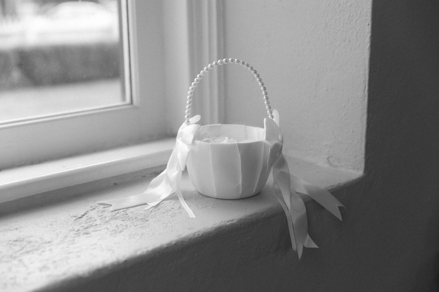Black and white photograph showing a white porcelain coffee cup sitting on a windowsill with natural light streaming in.