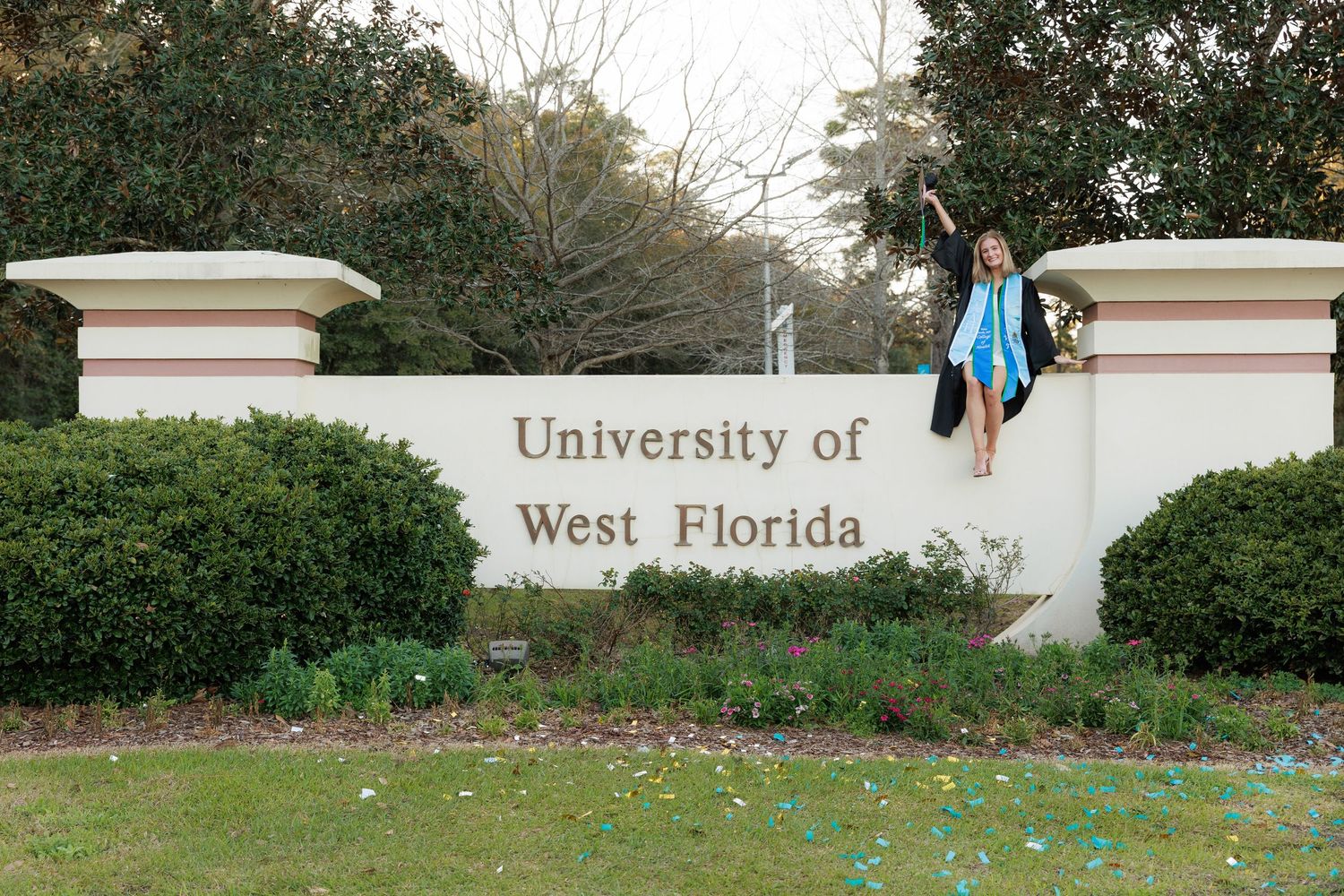 Colorful Easter eggs scattered across a grassy lawn near a university entrance sign during a springtime celebration.