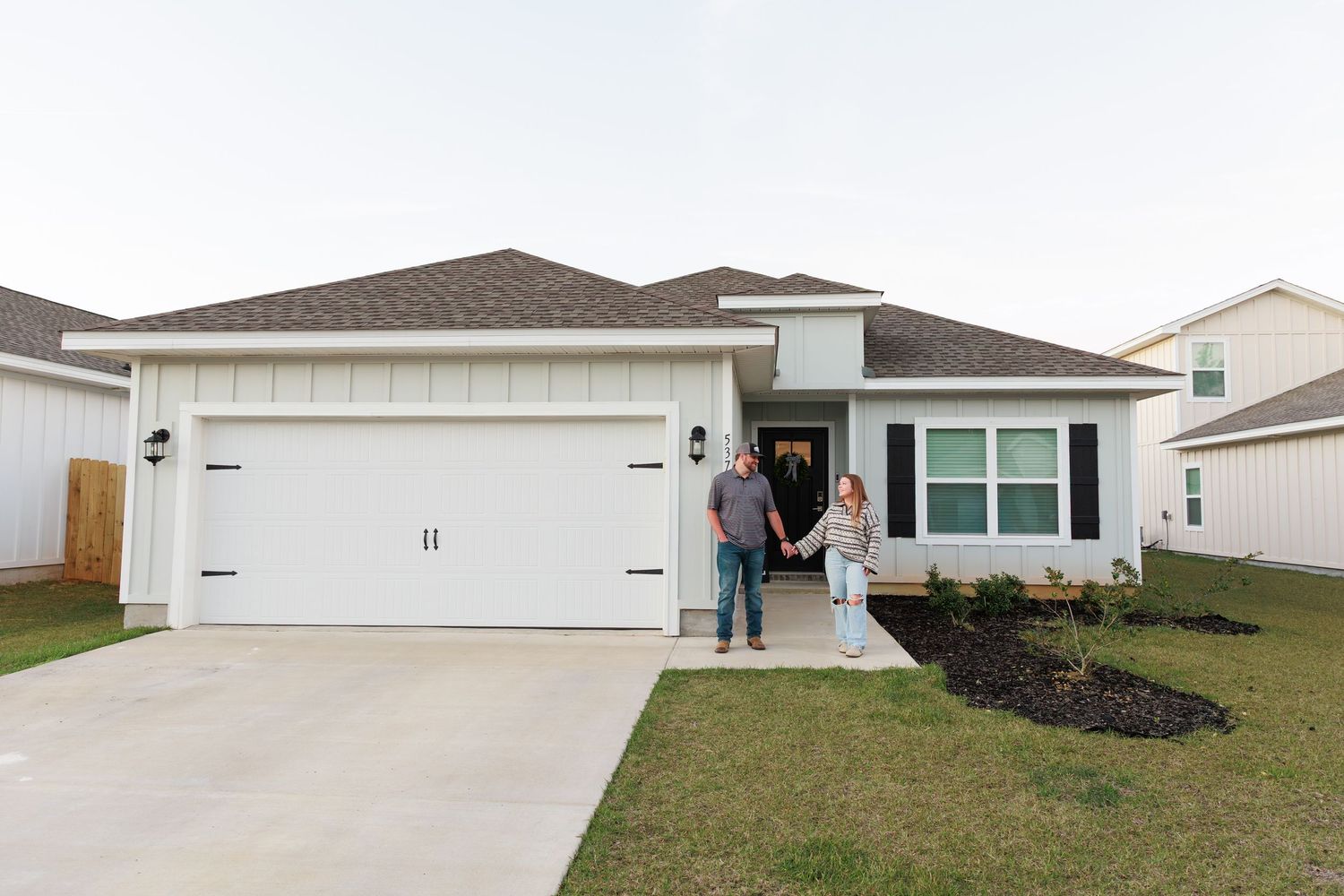 Exterior views of single-family homes with garages and lawns in a residential neighborhood.
