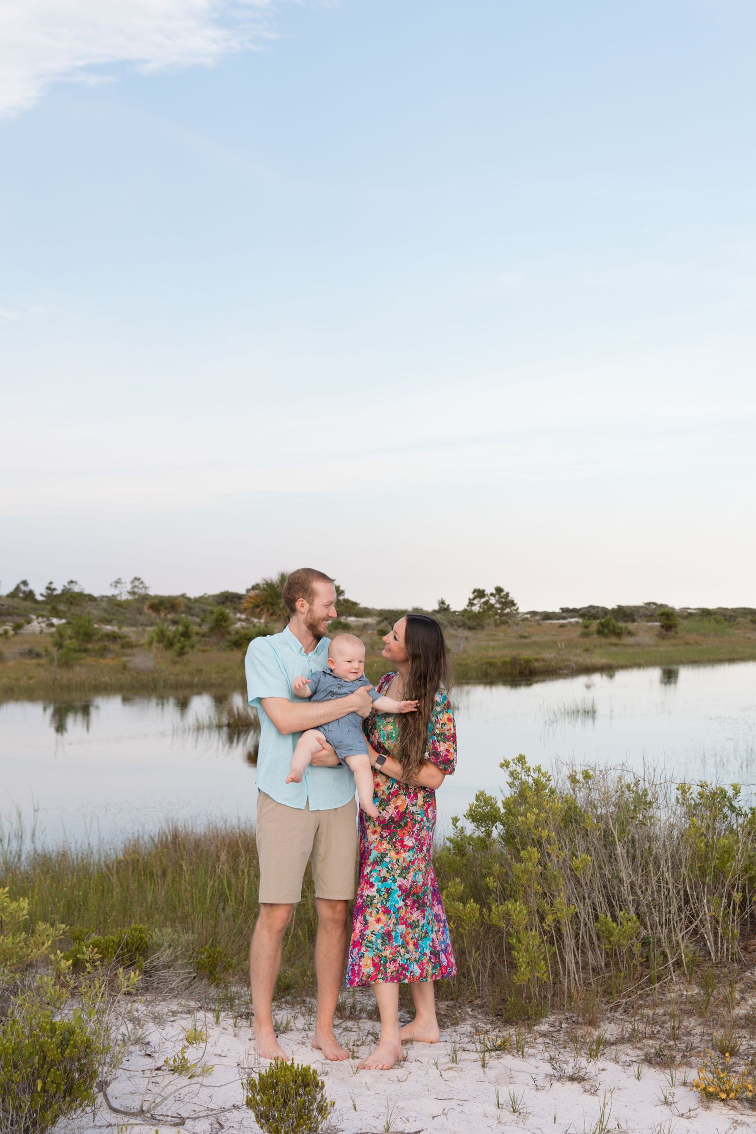 A coastal family portrait session features loving interactions against a marshy beach landscape.