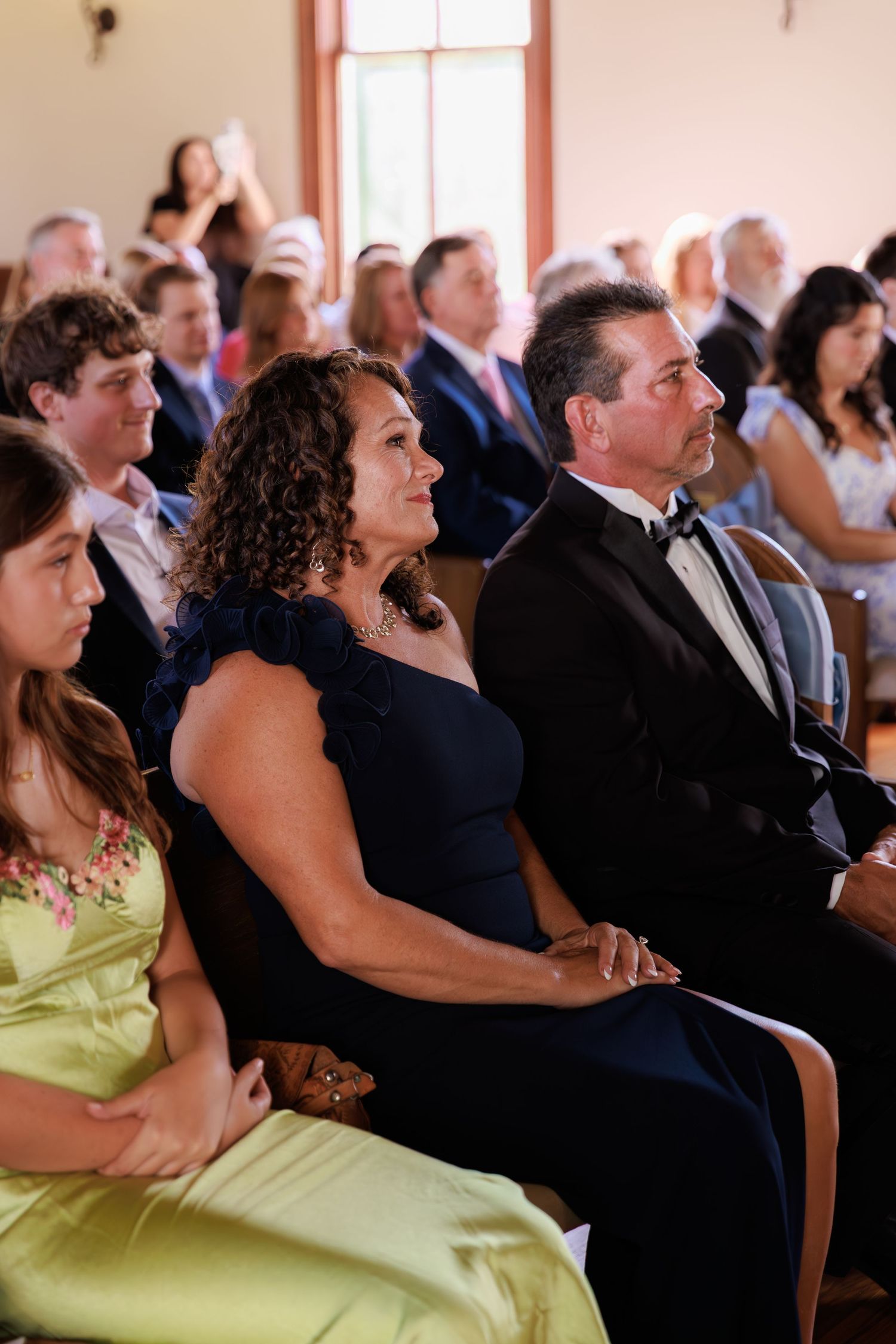 Wedding guests seated in formal attire watch an emotional ceremony in a church sanctuary.