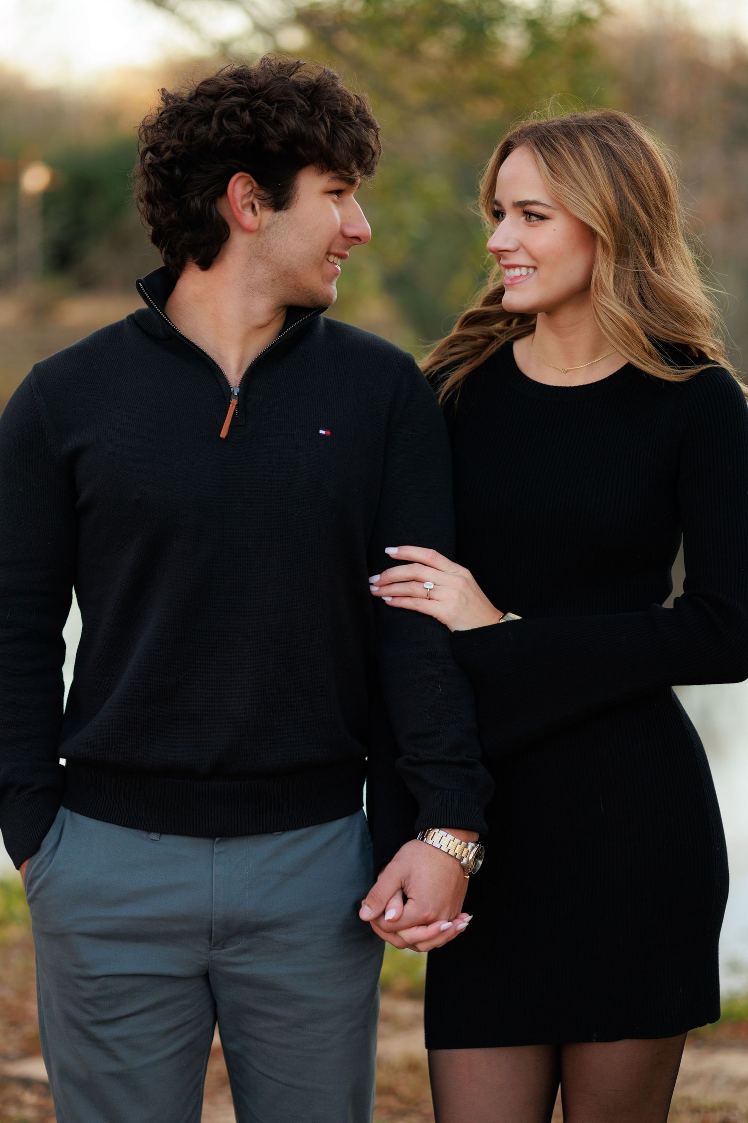 Couple in coordinated black outfits sharing a tender moment outdoors during golden hour.