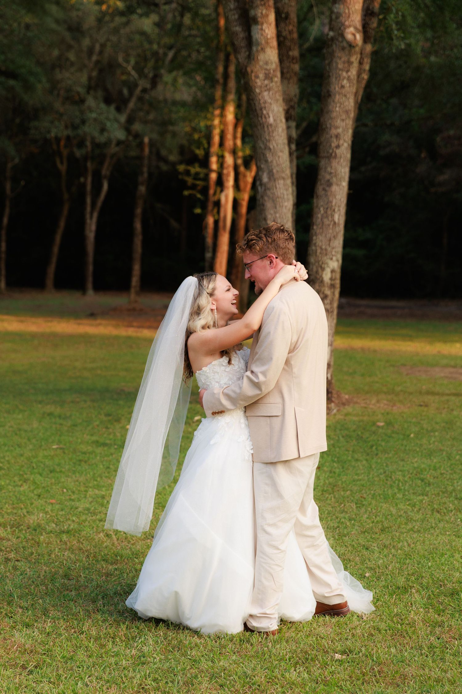 A romantic sequence of a couple in wedding attire dancing together on a grassy lawn at sunset.