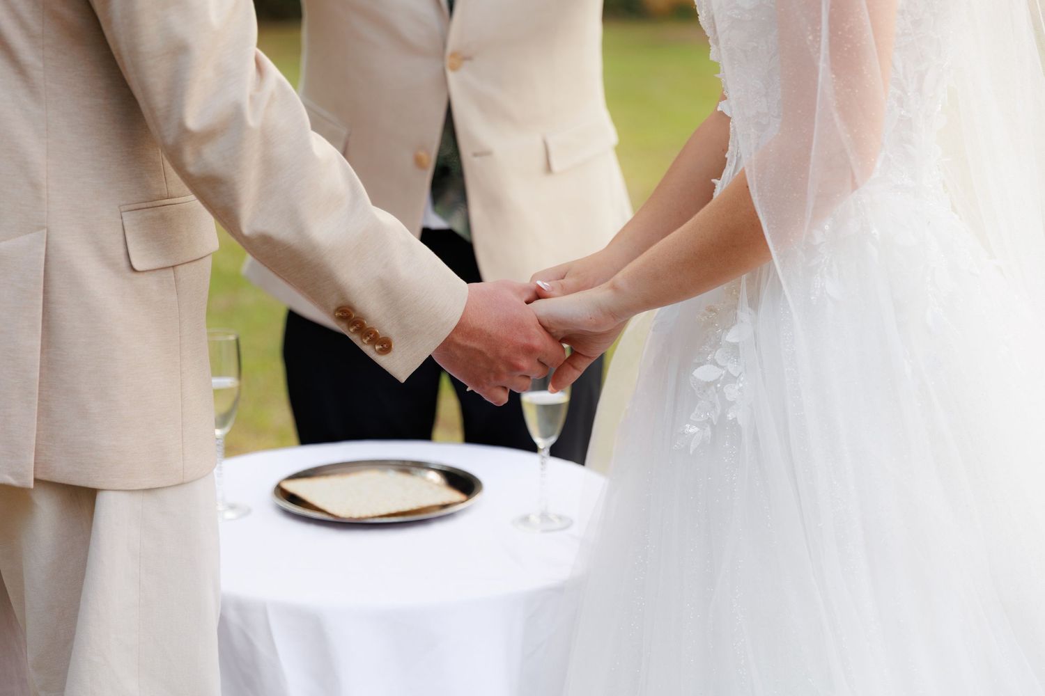 Wedding couple signs marriage certificate with witnesses and officiant at outdoor ceremony.