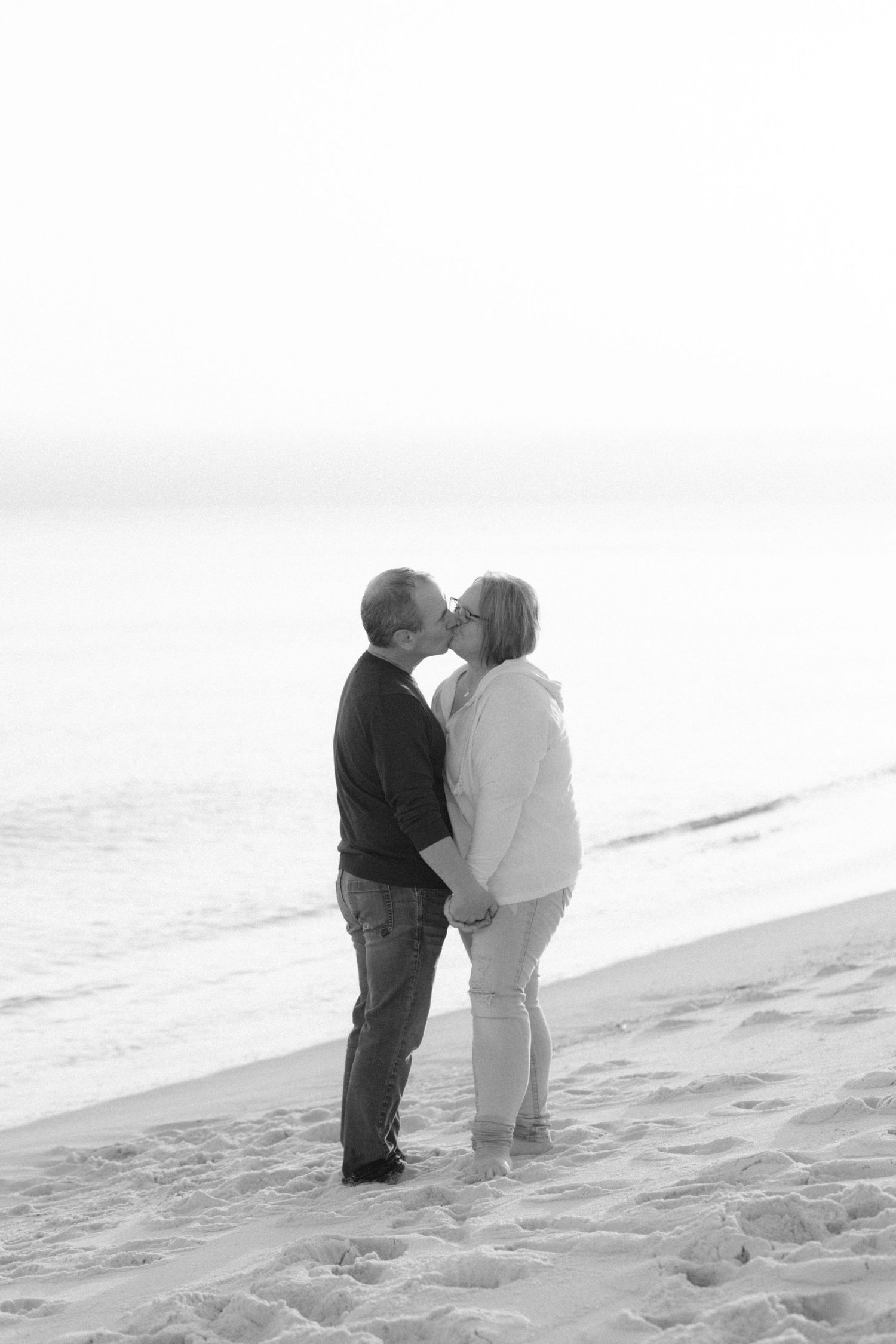 Two children share a sweet kiss while standing in the snow on a winter day.