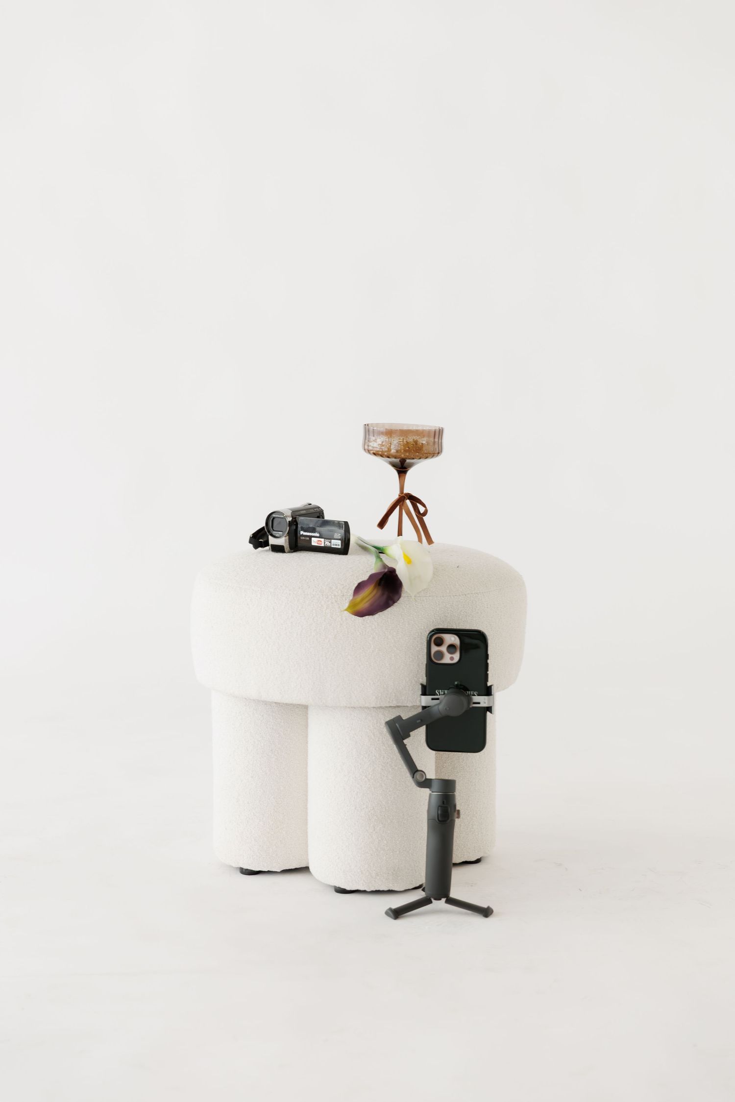 Creative still life with camera equipment arranged on white toilet paper rolls against white background.