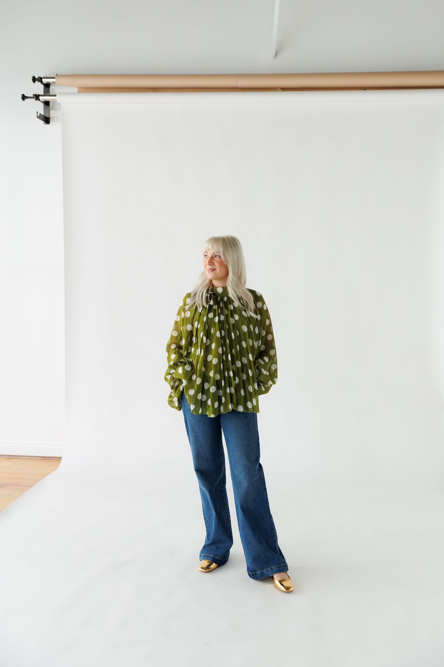 Four sequential photos showing someone in blue jeans wearing a dramatic ruffled green and yellow floral top against a white backdrop.