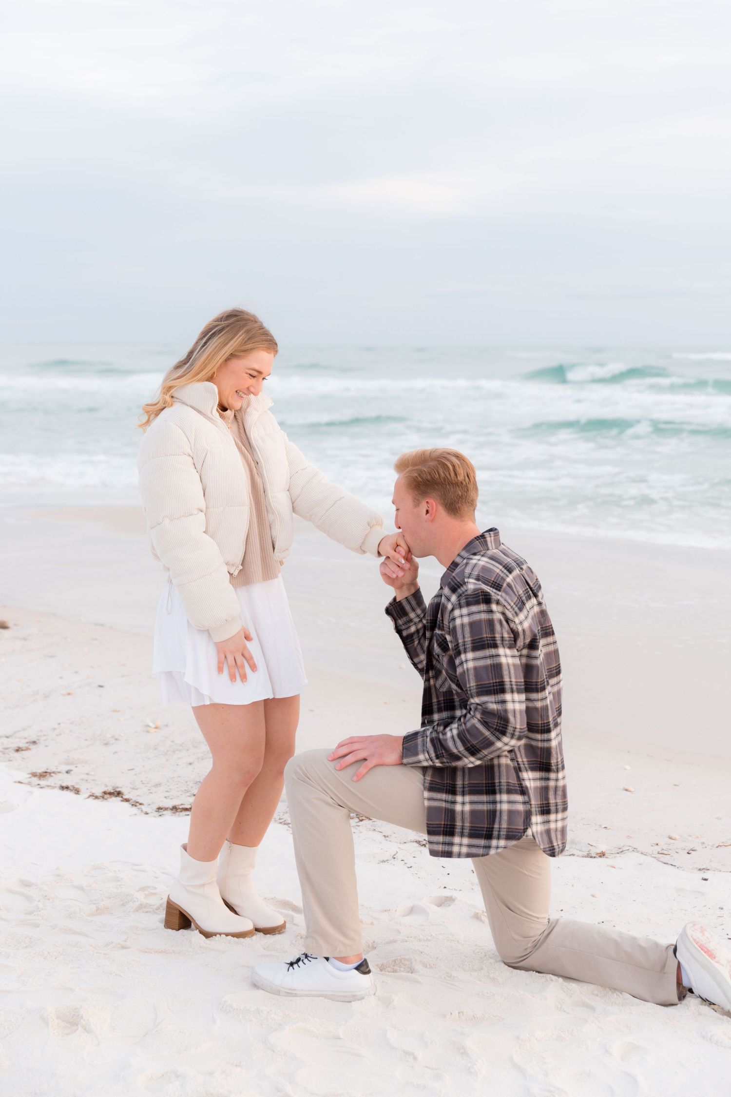 A surprise beach proposal moment captured with ocean waves in the background.