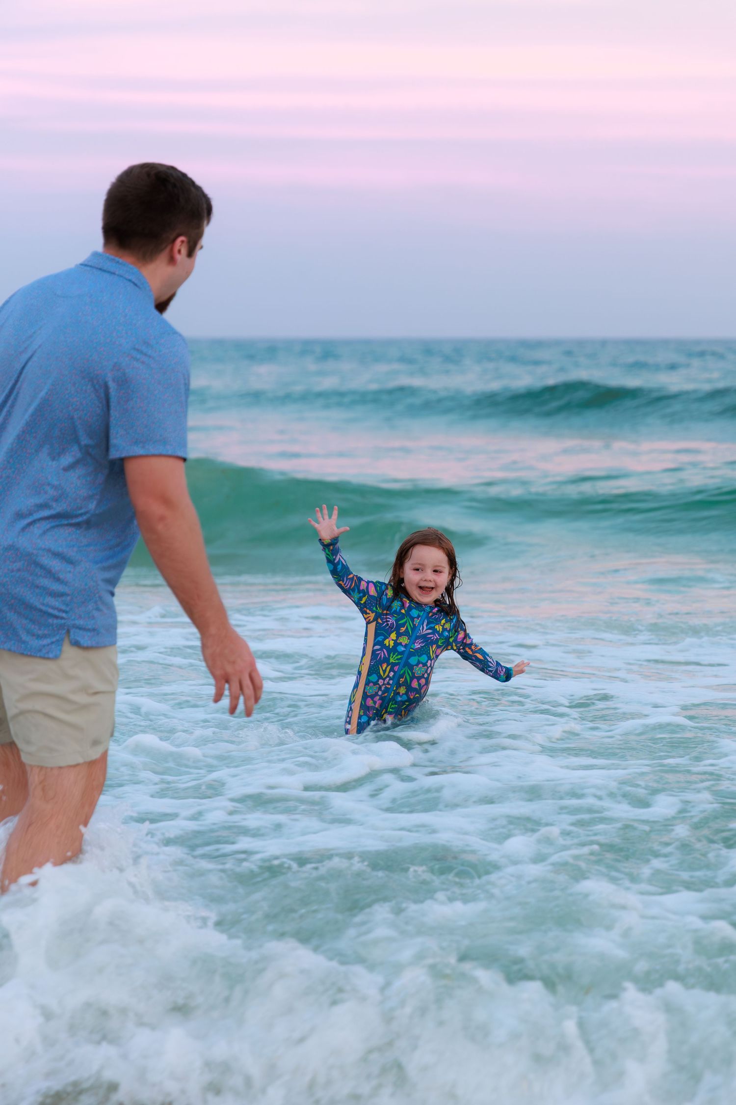 A sequence of photos showing a child playing in ocean waves at the beach while wearing a blue patterned swimsuit.