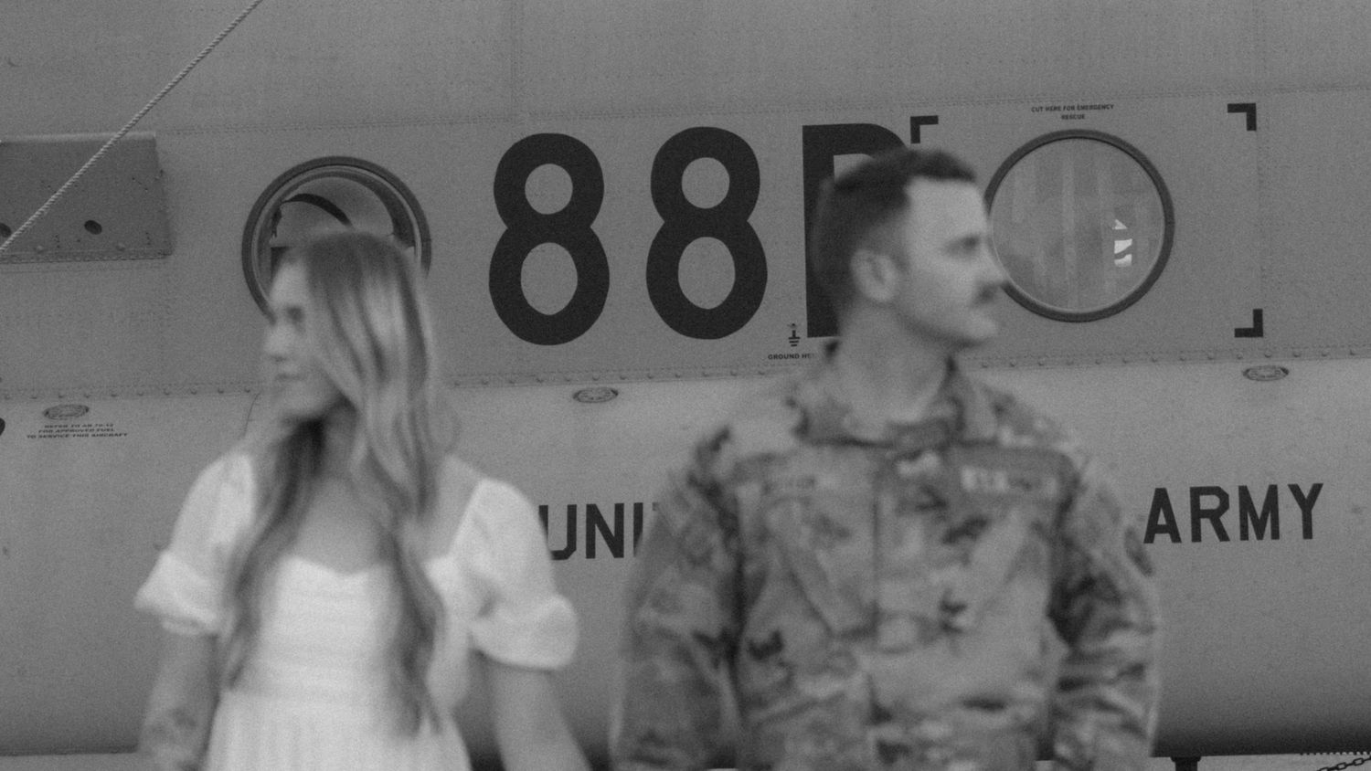 Military couple poses for photo in front of aircraft with number 88.