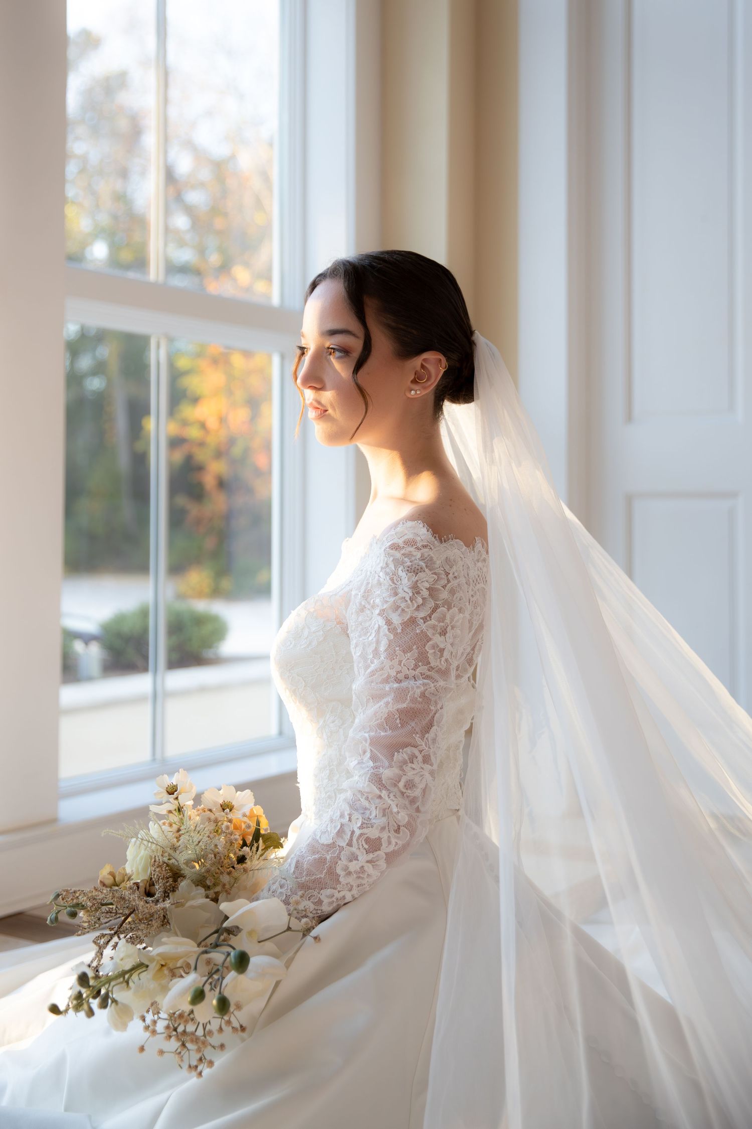 Elegant bridal portraits by sunlit windows showcasing lace details and flowing veil.