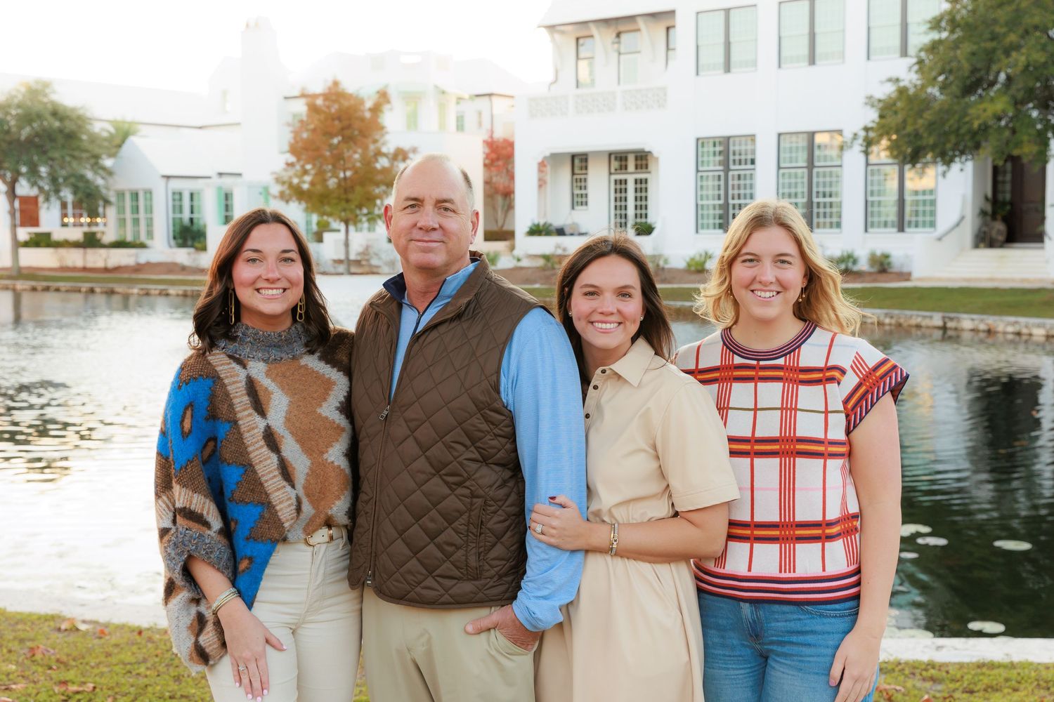 A cheerful family gathering poses together by the water on a sunny autumn day.