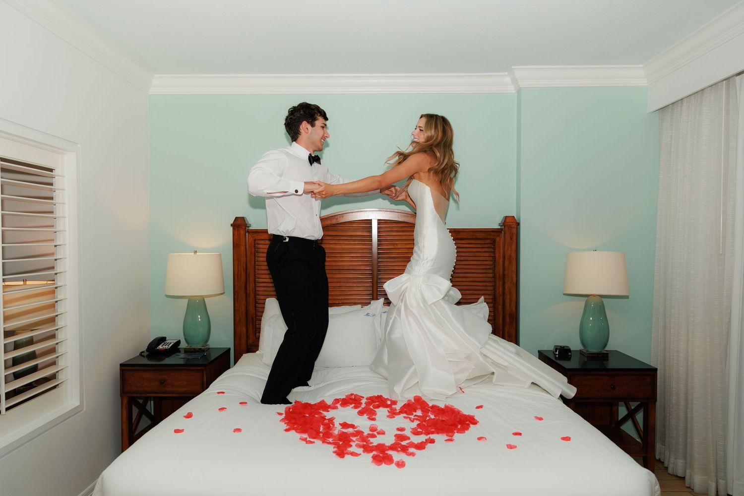 A romantic wedding photoshoot sequence showing interacting with rose petals scattered on a white bed.