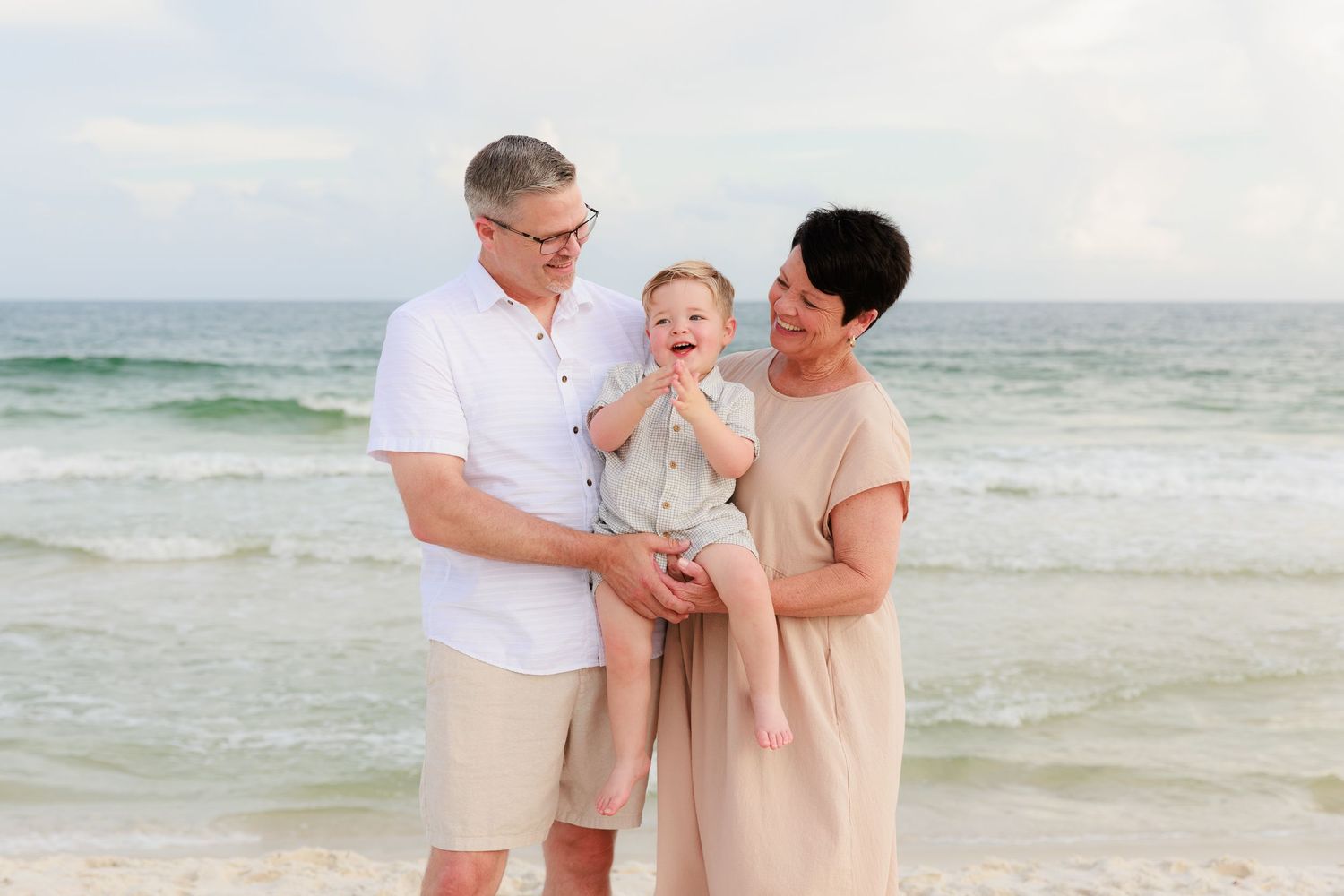 Couple shares joyful moment while walking along sandy beach with ocean waves in background.
