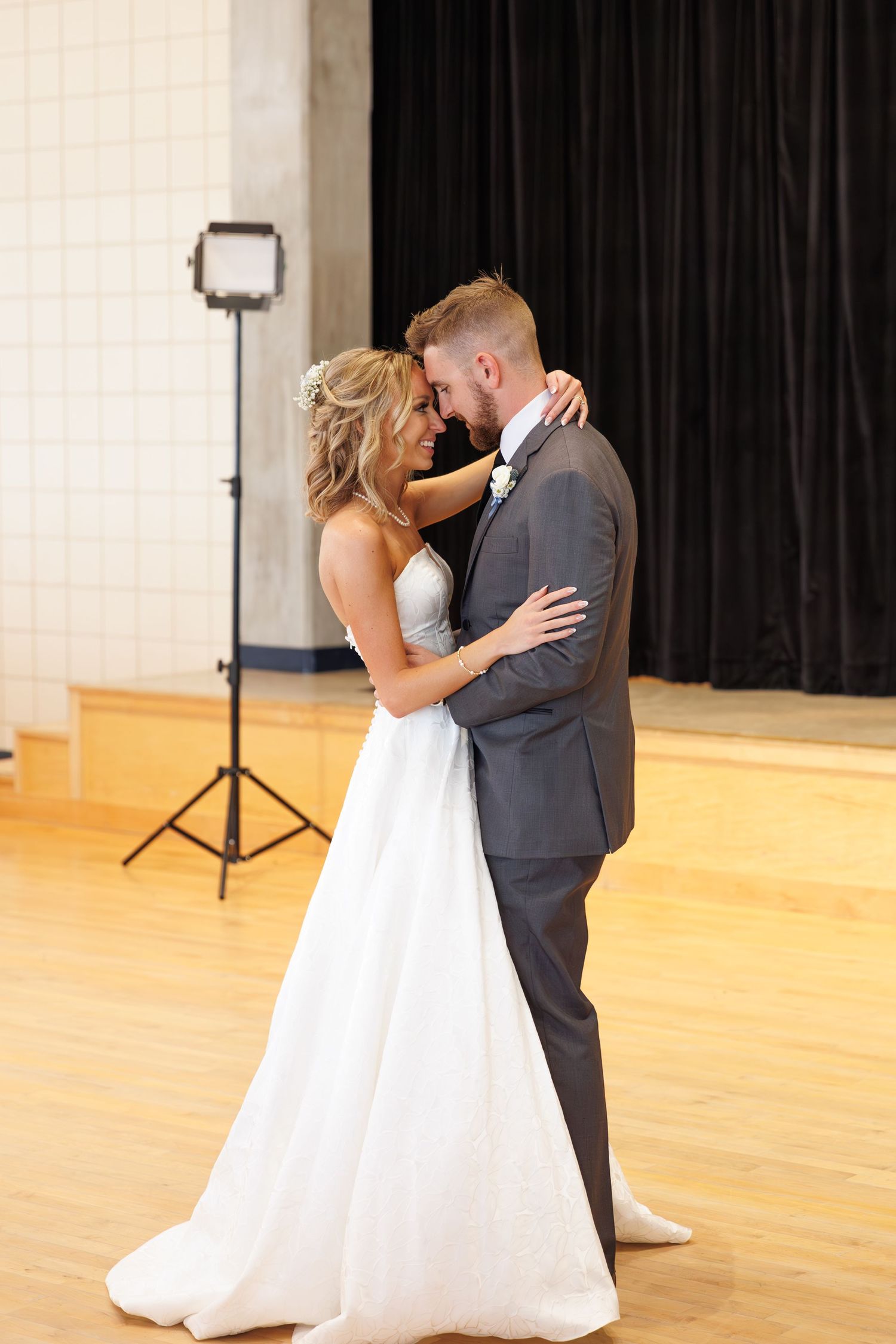 Romantic first dance moment captured in an elegant reception hall with hardwood floors.
