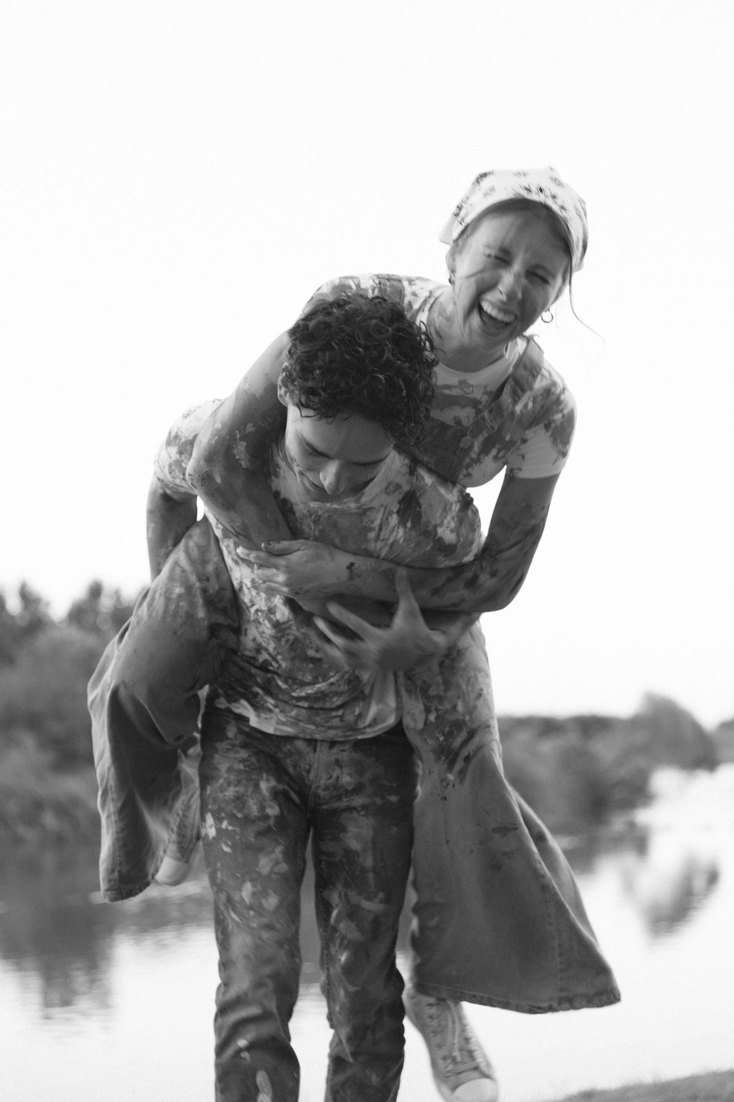 Black and white photo series showing two people playing and splashing in water with joyful expressions.