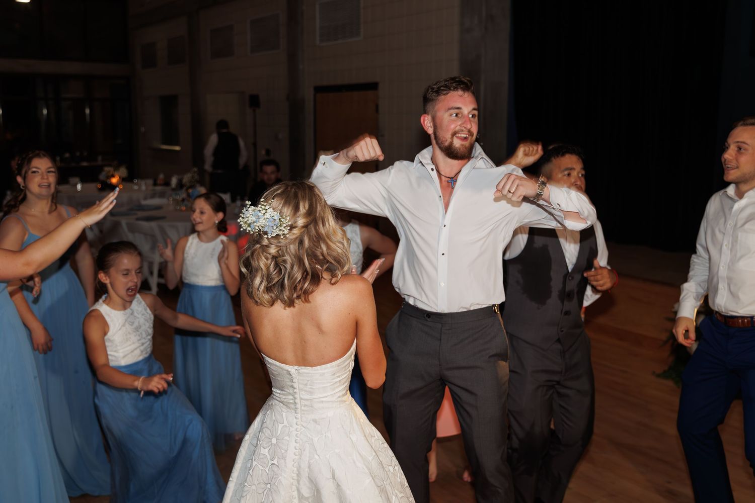 Energetic dancing at a wedding reception with guests in formal attire.