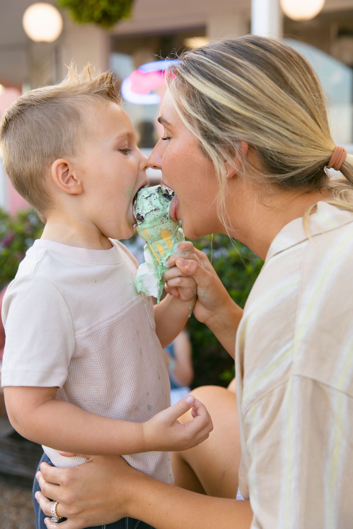 Parent and child sharing a playful moment while eating mint ice cream together.