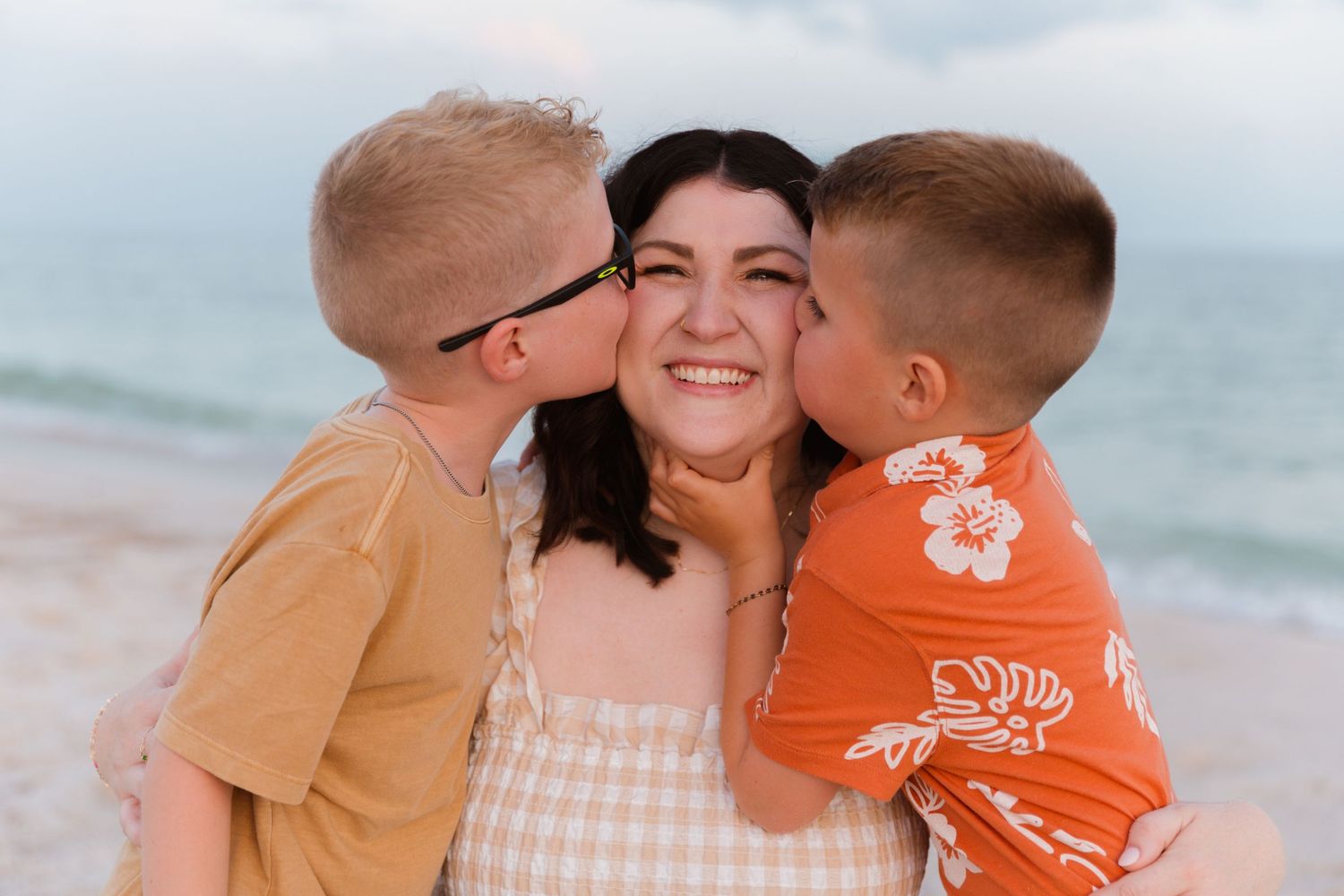Sweet family moment captured on beach with ocean backdrop.