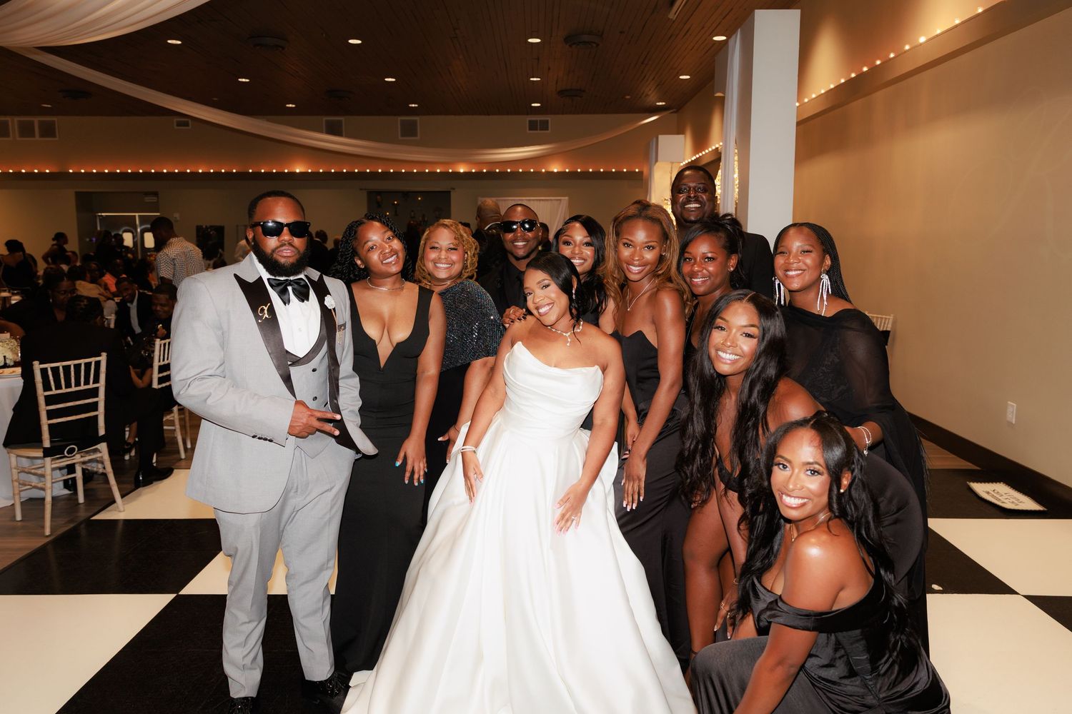 Wedding party poses together for a group photo in formal attire at the reception venue.