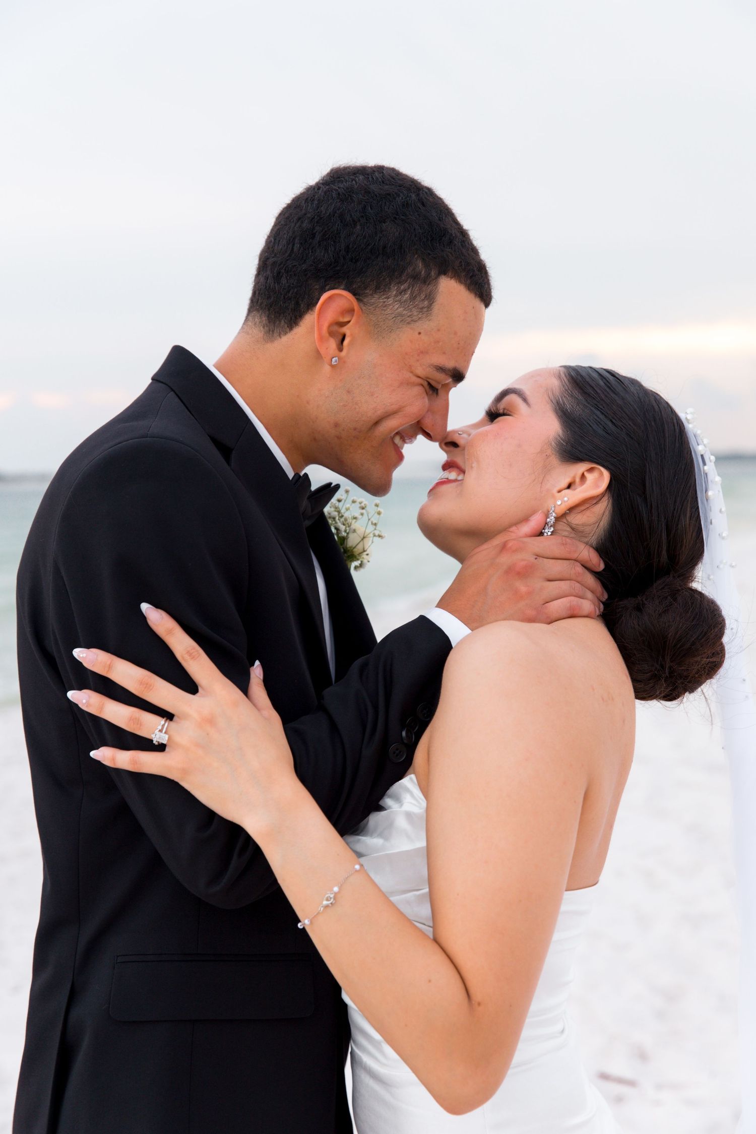Intimate candid moment of bride and groom laughing together on beach.
