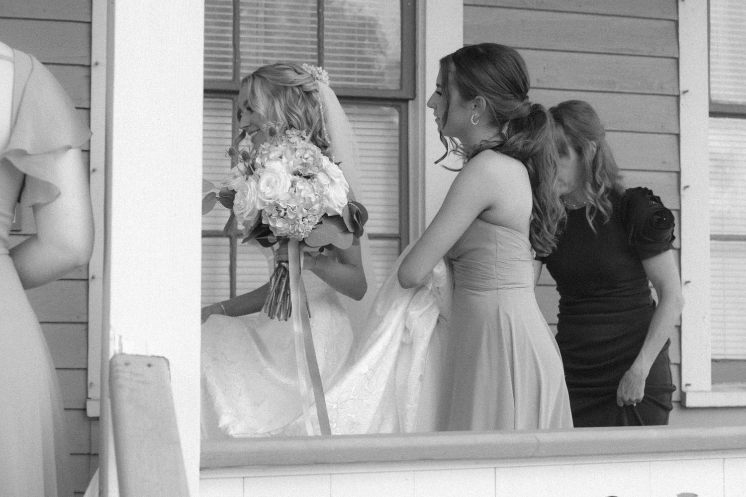 Bridal party peers through window while preparing for wedding ceremony.