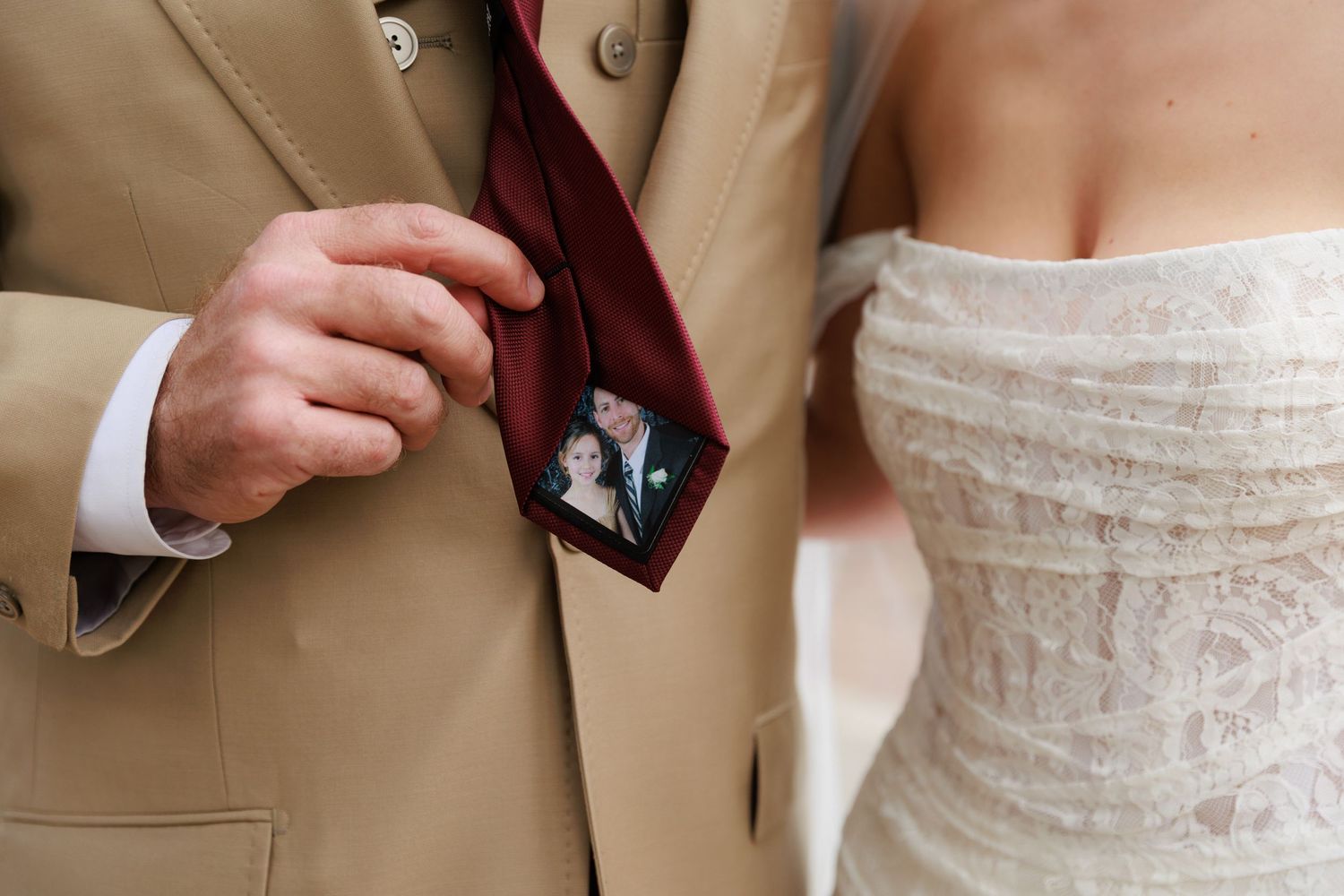Close-up view of someone adjusting a white lace wedding dress bodice with delicate details.