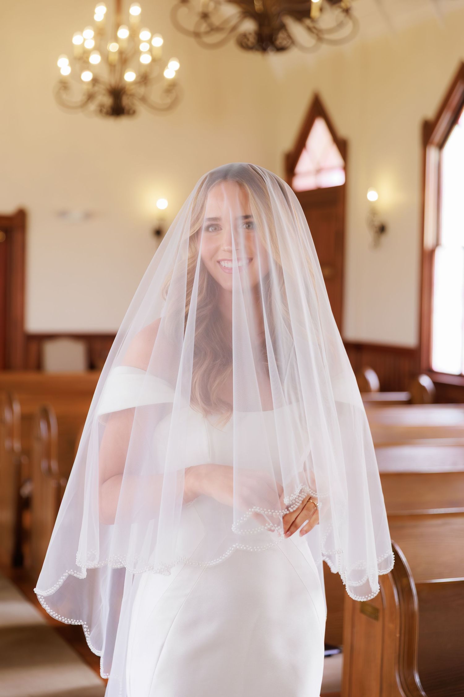 Ethereal bridal portraits with a flowing veil capture romantic moments in a chapel setting.
