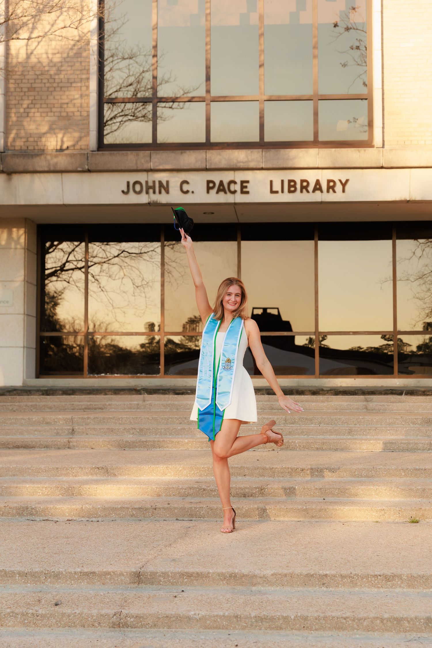 A series of photos showing a person in a blue dress posing on the steps of the John C. Pace Library at sunset.