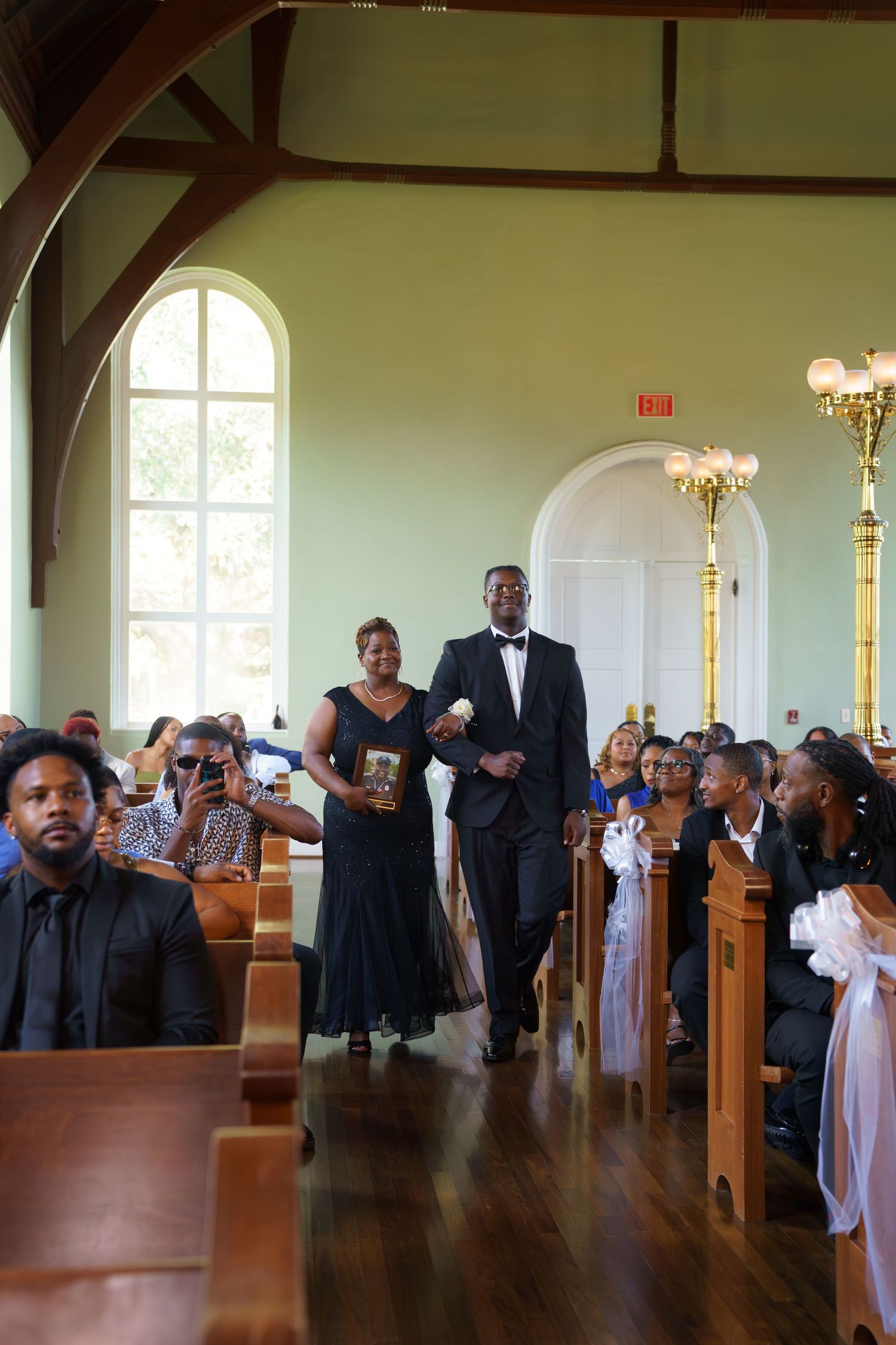 Wedding ceremony guests and wedding party gather in a traditional church sanctuary with wooden beams.