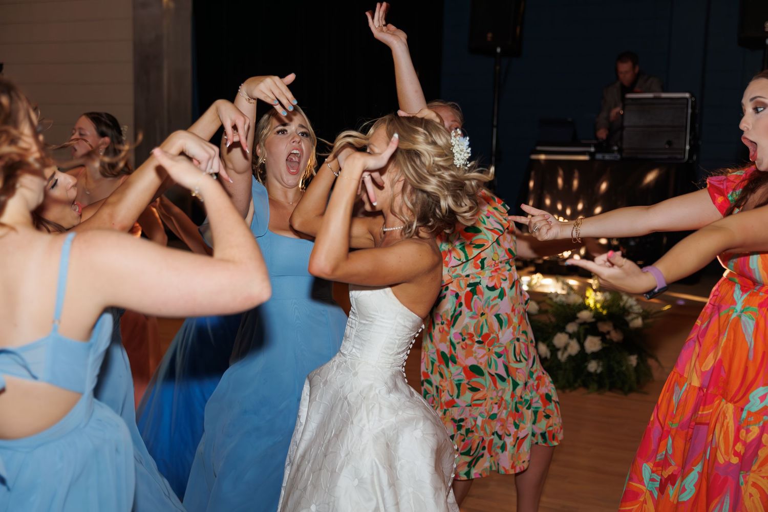 Energetic dancing and celebration at a wedding reception with guests in colorful attire.