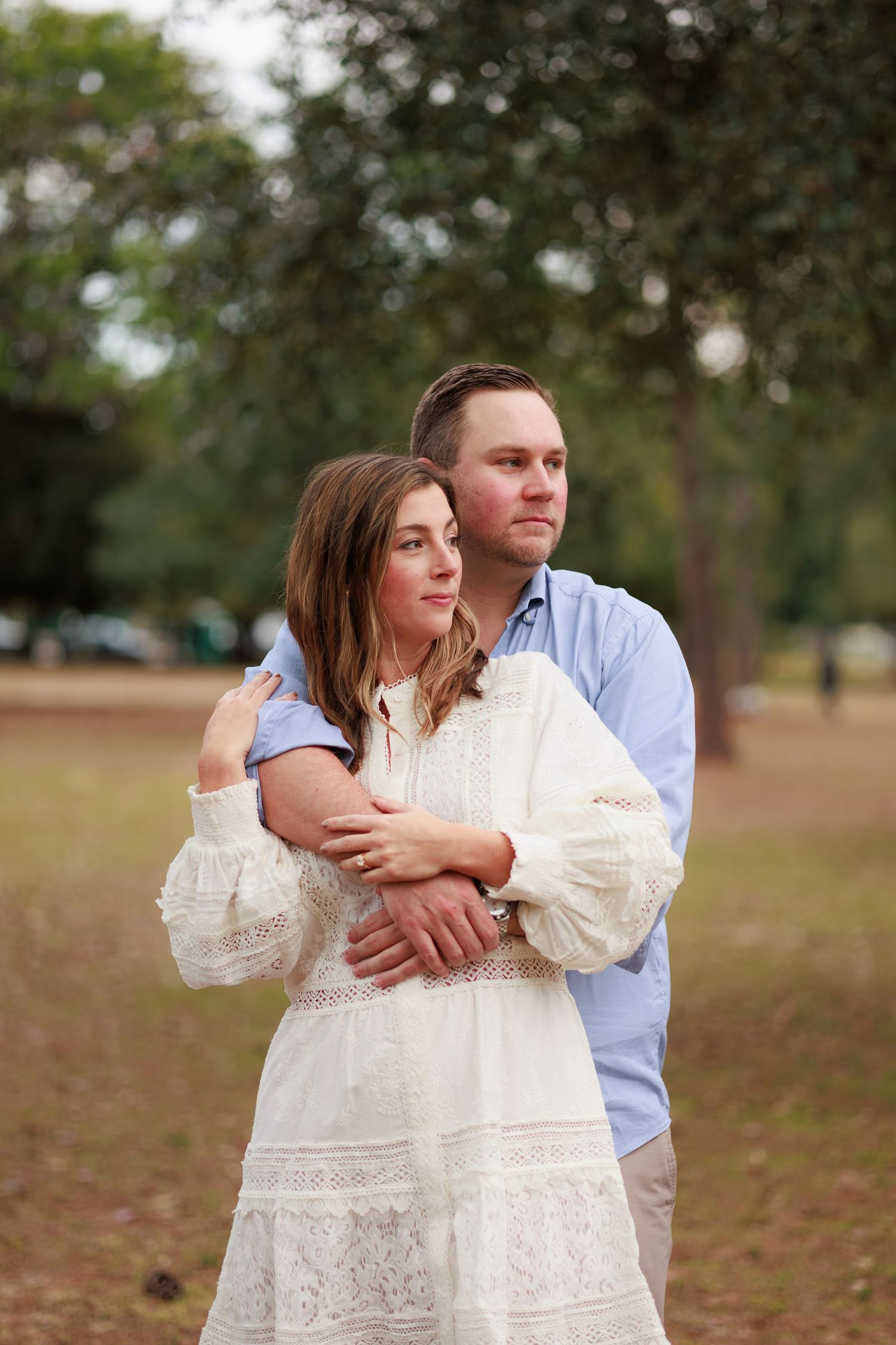A romantic embrace captured in a field during a couples photoshoot with soft natural lighting.