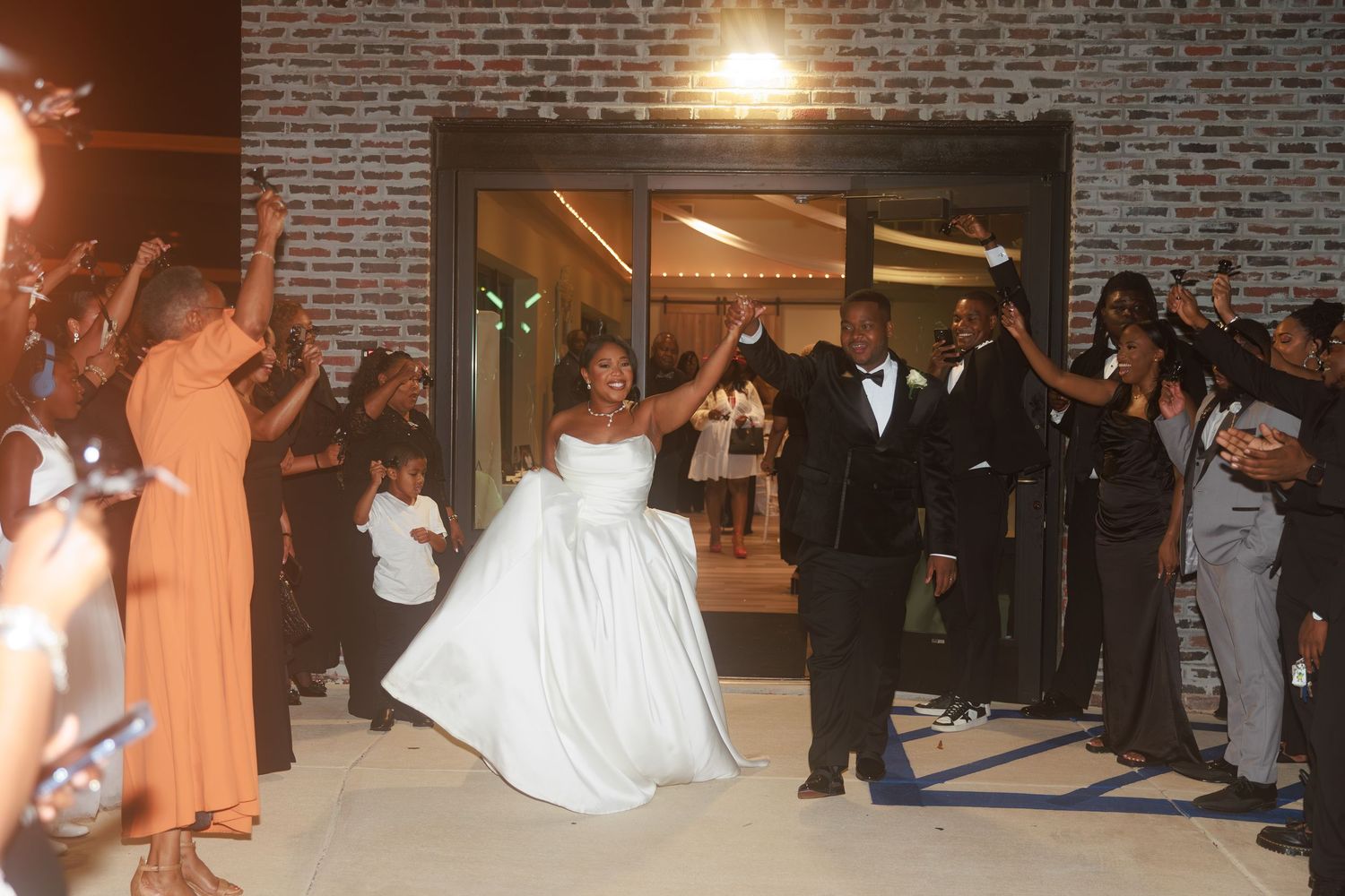 A sequence of dance moves at a wedding reception showing guests performing a line dance in front of a brick wall.