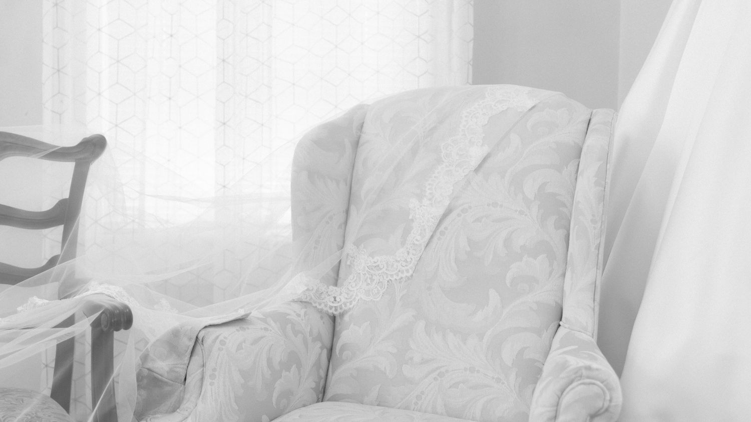 Soft white bedding and pillows in a bright, airy bedroom with natural light streaming through windows.