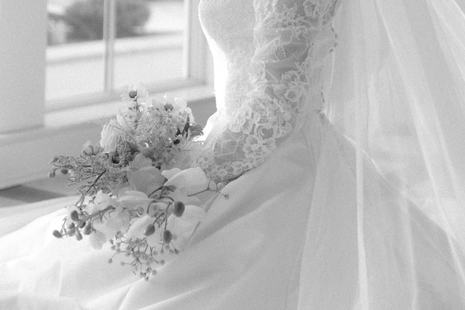 White wedding dress details showing intricate lace patterns and delicate floral embellishments on tulle fabric.