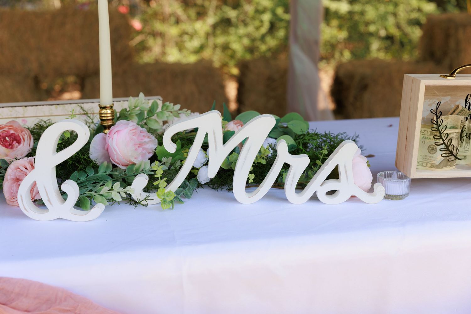 Wedding reception table decorated with pink and white floral arrangements and elegant script signage.