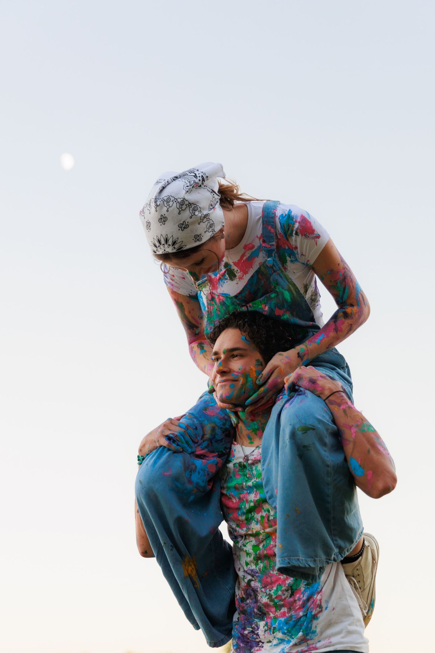Two people in floral print clothing embrace in a tender dance pose against a light background.