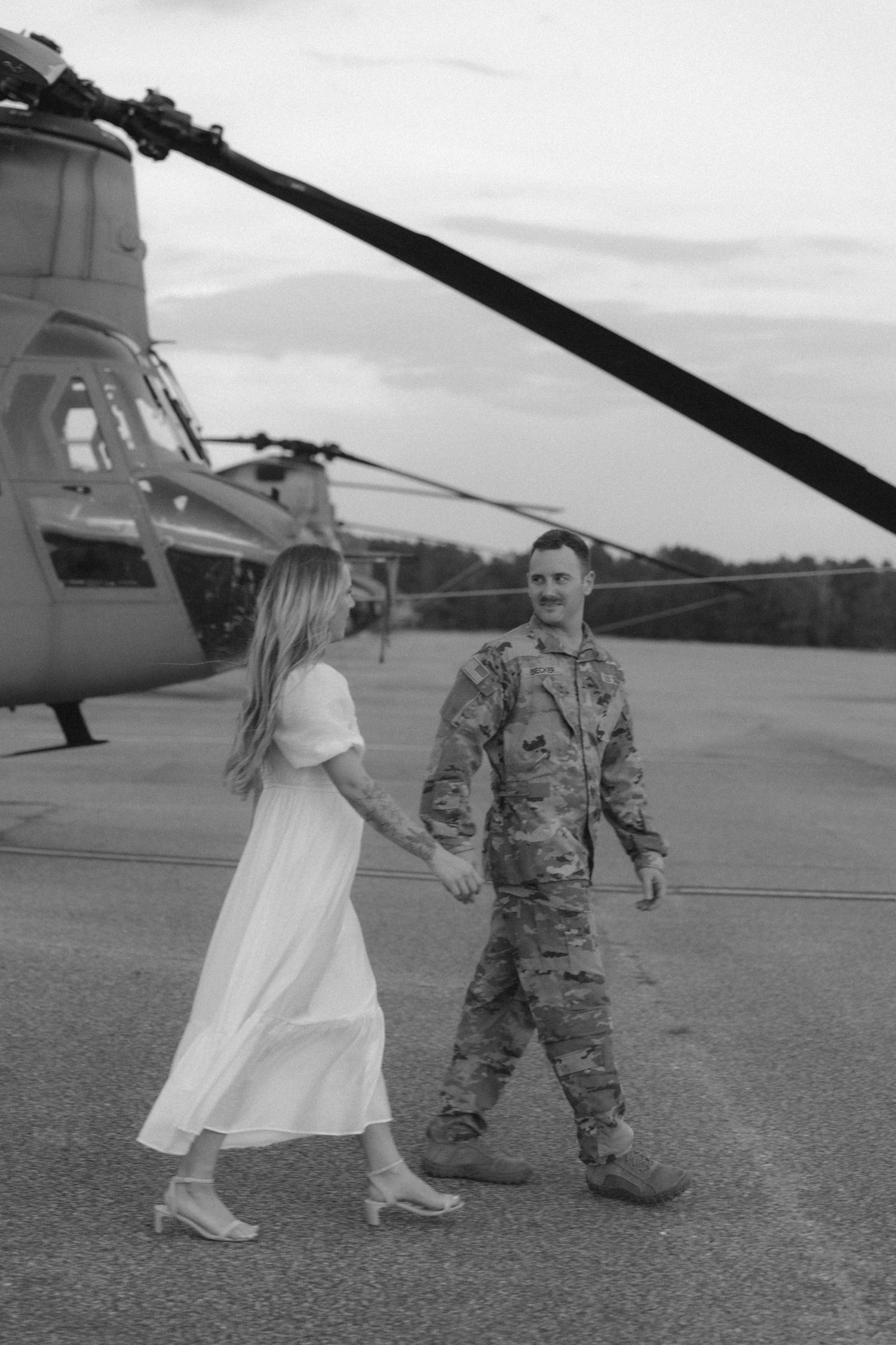 Dancing and walking figures silhouetted against bright daylight by a military helicopter.